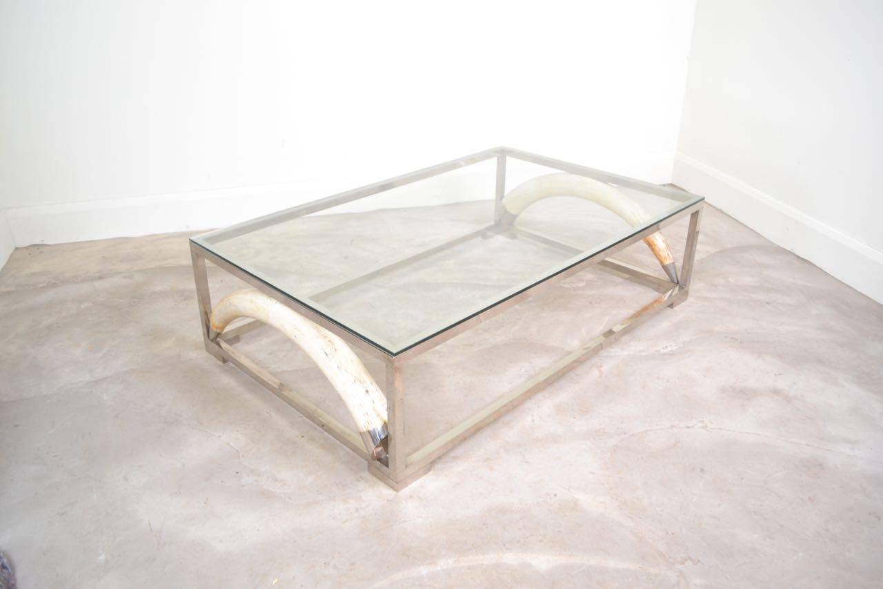 Fabulous large scale coffee table with resin cast faux Elephant tusks mounted into the frame. The original glass is good quality and is 1 cm thick.    
   