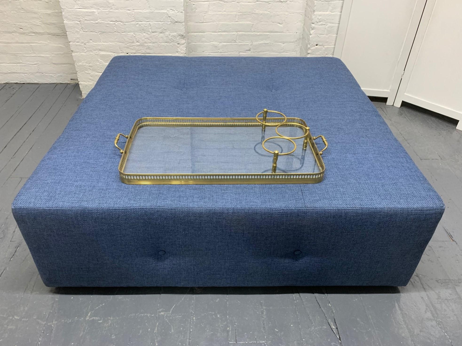 Our custom designed large-scale tufted ottoman with a brass and glass serving tray. The glass tray has a decorative brass trim and three brass compartments for bottles.