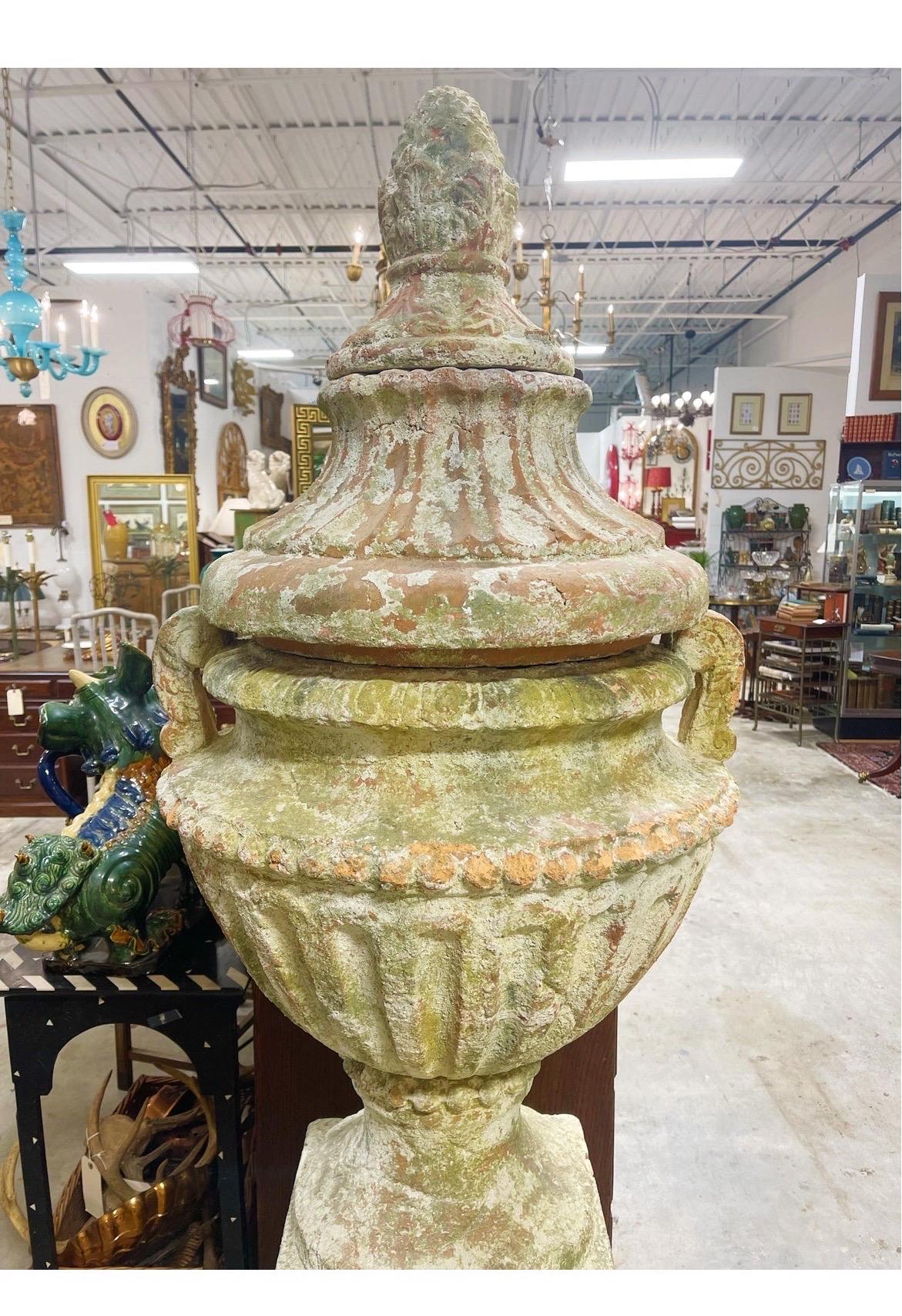 A large scale 4 piece terracotta urn on stand. In the neoclassical taste and having a distressed and weathered appearance.