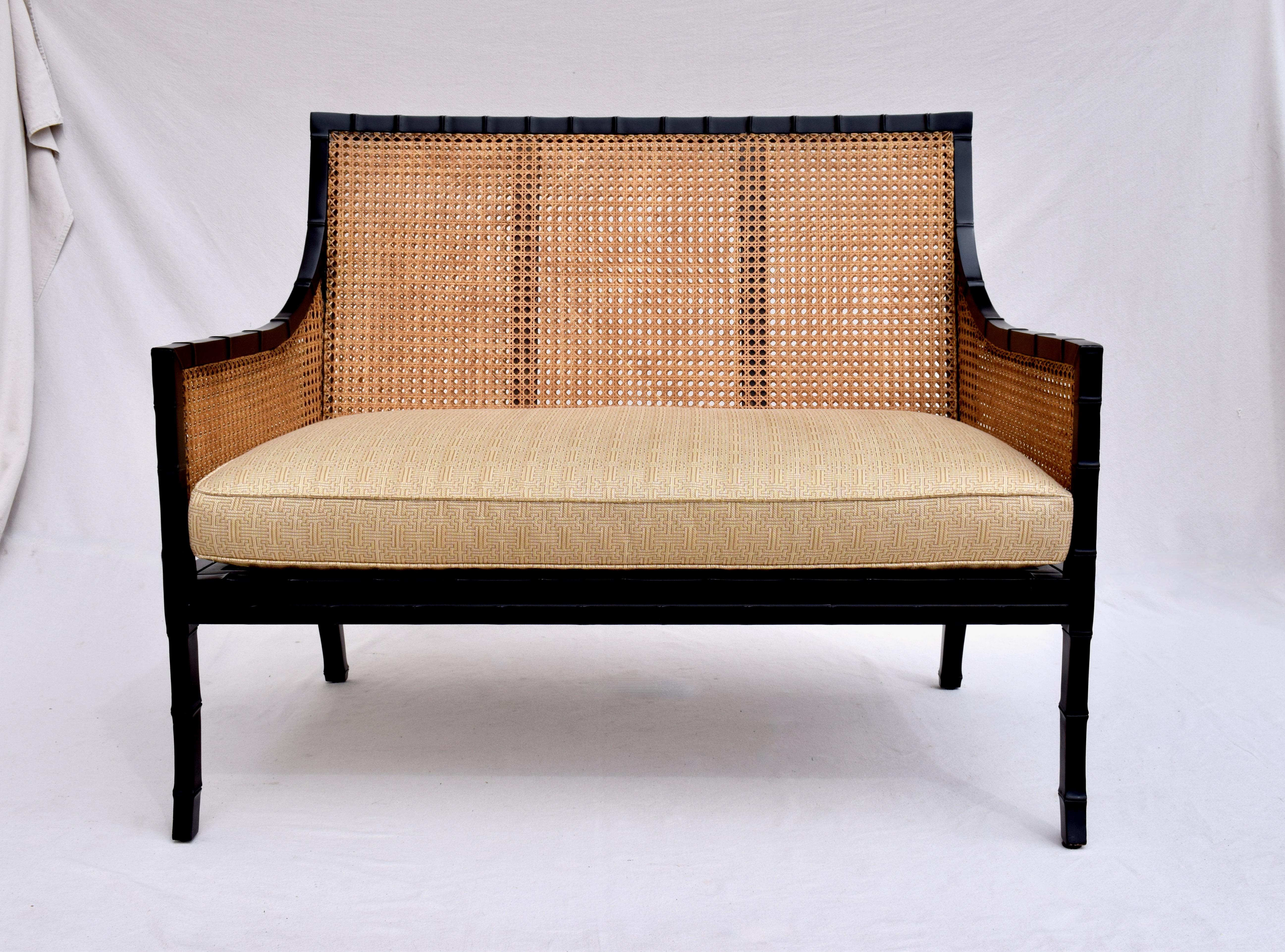 A handsome double sided cane settee of heavy ebony lacquered bamboo form wood expertly crafted to absolute perfection. Large in scale this custom beauty features three expertly upholstered goose down cushions designed to highlight a special space.