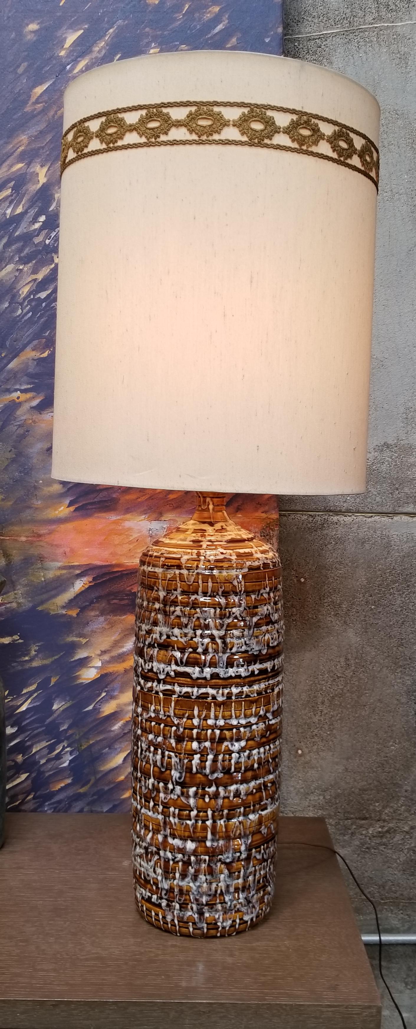 A 1960s ceramic lamp with a multi-color drip glaze. Primary colors are white, black and light brown. Vintage shade included.

Ceramic portion of lamp measures 23.5 inches in height.