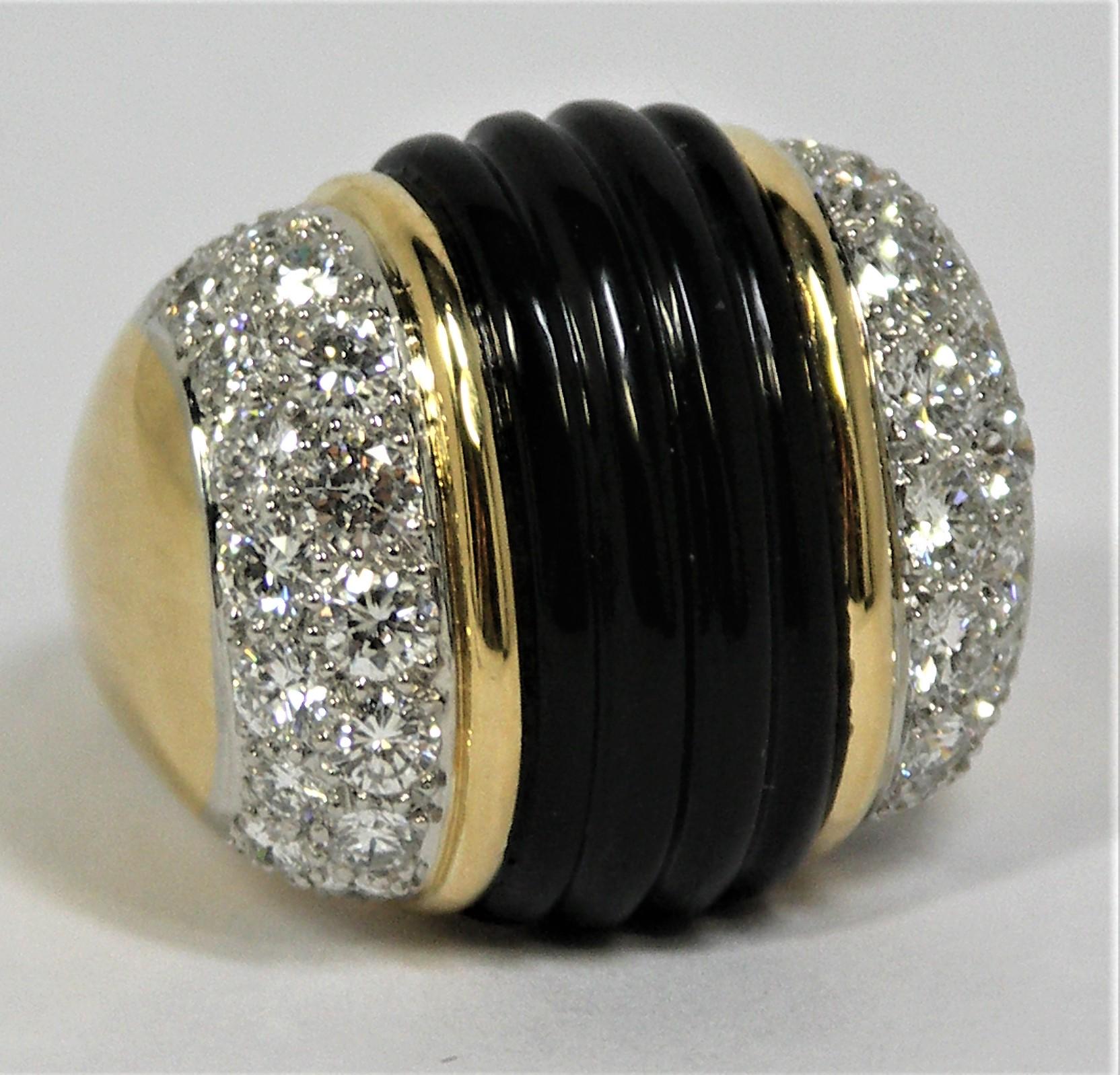 A large scale 18K Yellow Gold statement ring, inset with a center section 
of fluted onyx, and with two Platinum plates set with 38 Round Brilliant Cut Diamonds weighing an approximate total of 4.25Ct of overall F/G Color 
and VS1 Clarity. Measuring