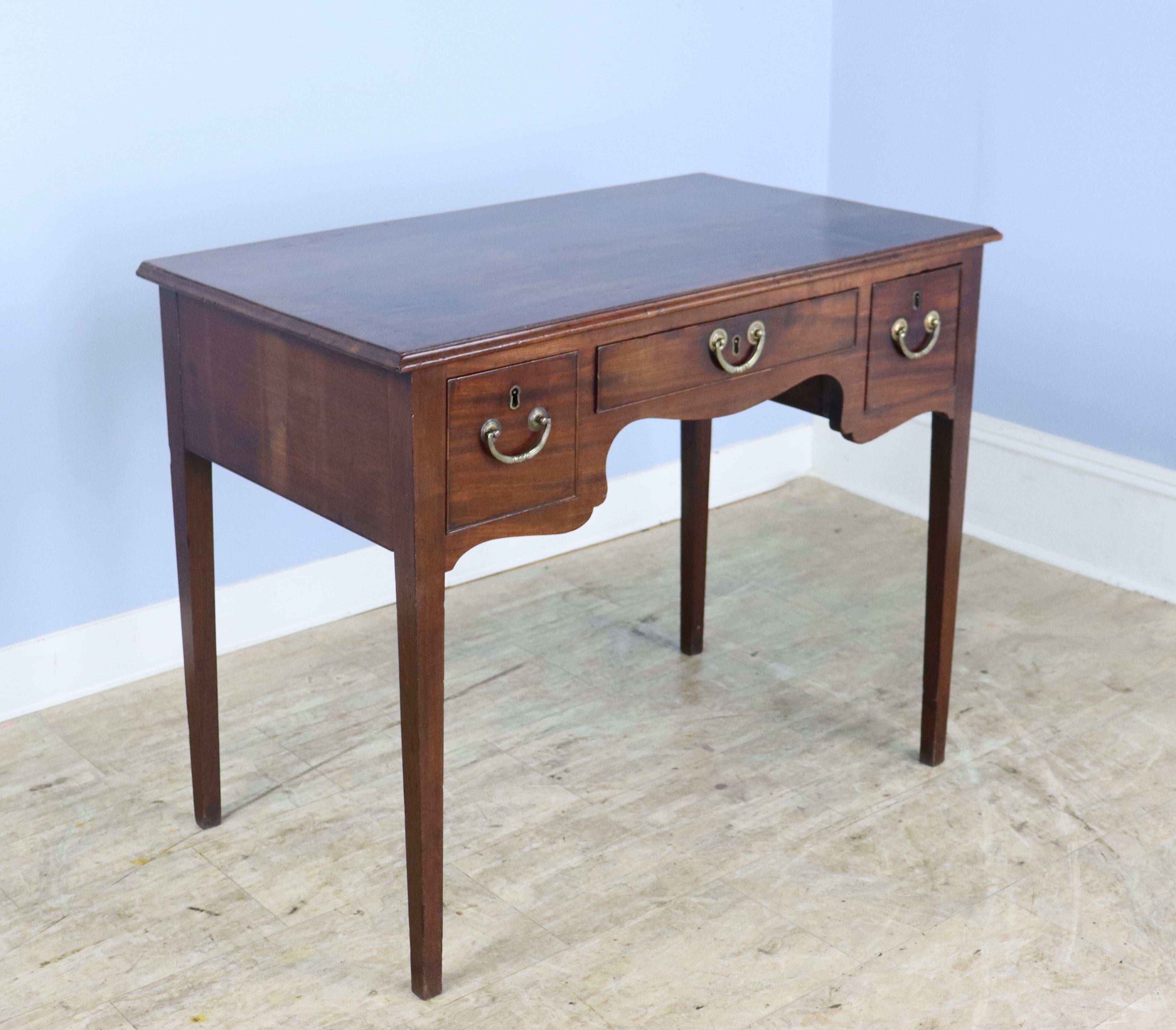 A large scale Georgian lowboy or side table with lovely scalloped aprons with three front drawers, all with good cockbeading at the edges. The top has a very handsome molding around the edge.  With lovely color and patina on the mahogany top, this