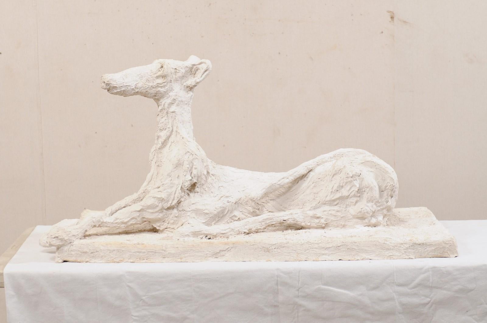 A large-sized French artisan created greyhound dog sculpture. This fabulous statue from France has been created in the image of a regal Greyhound dog, in alert laying position with head facing forward, front legs stretched out far in front, and tail