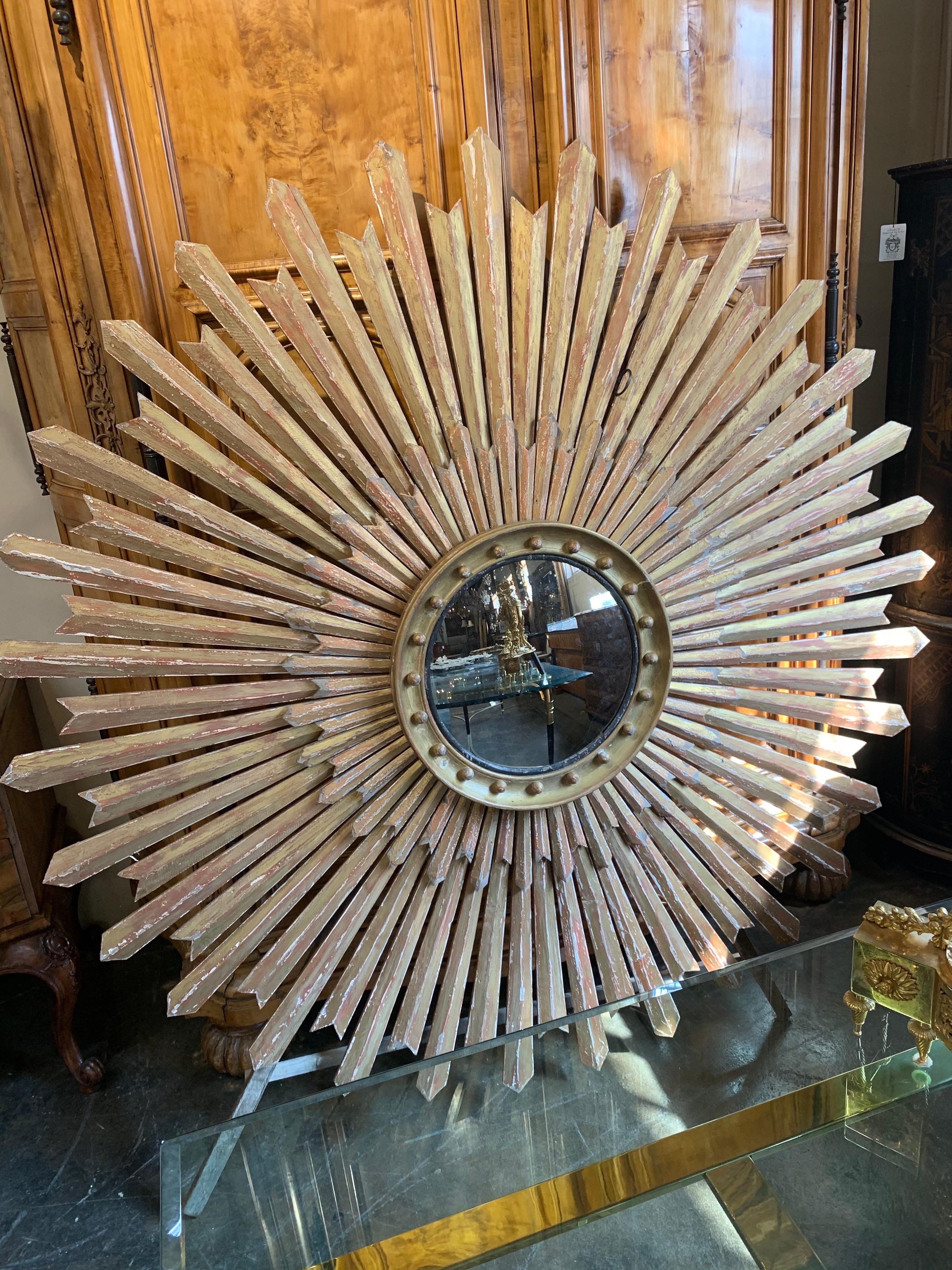 Fabulous large scale carved giltwood sunburst with convex mirror. Lovely patina with shades of gold, red and white. Makes a huge impact! Amazing!