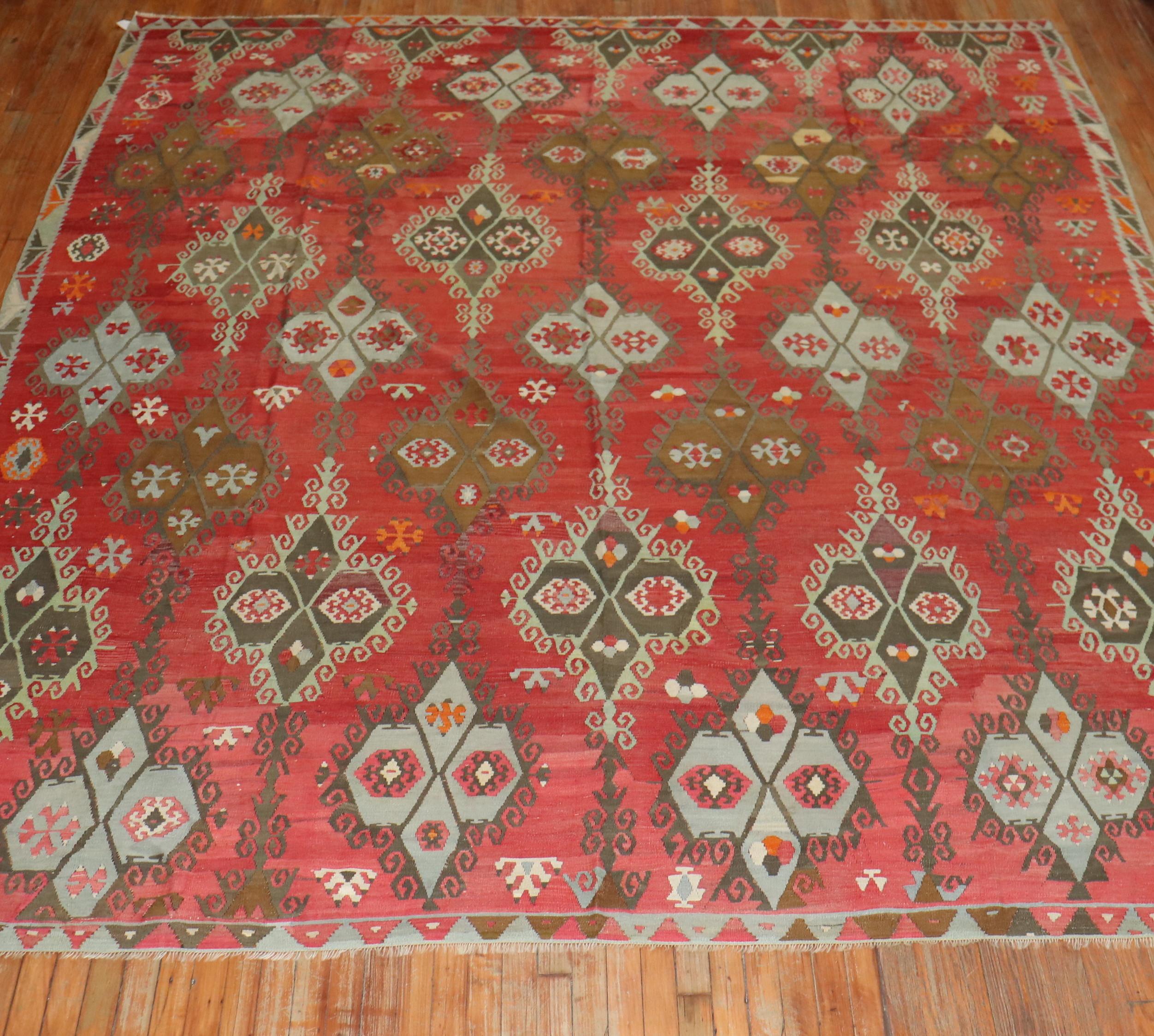 A fascinating Turkish Kilim flat-weave featuring a large scale all-over geometric and floral design on a striated red field,

circa 1900, measures: 9'9