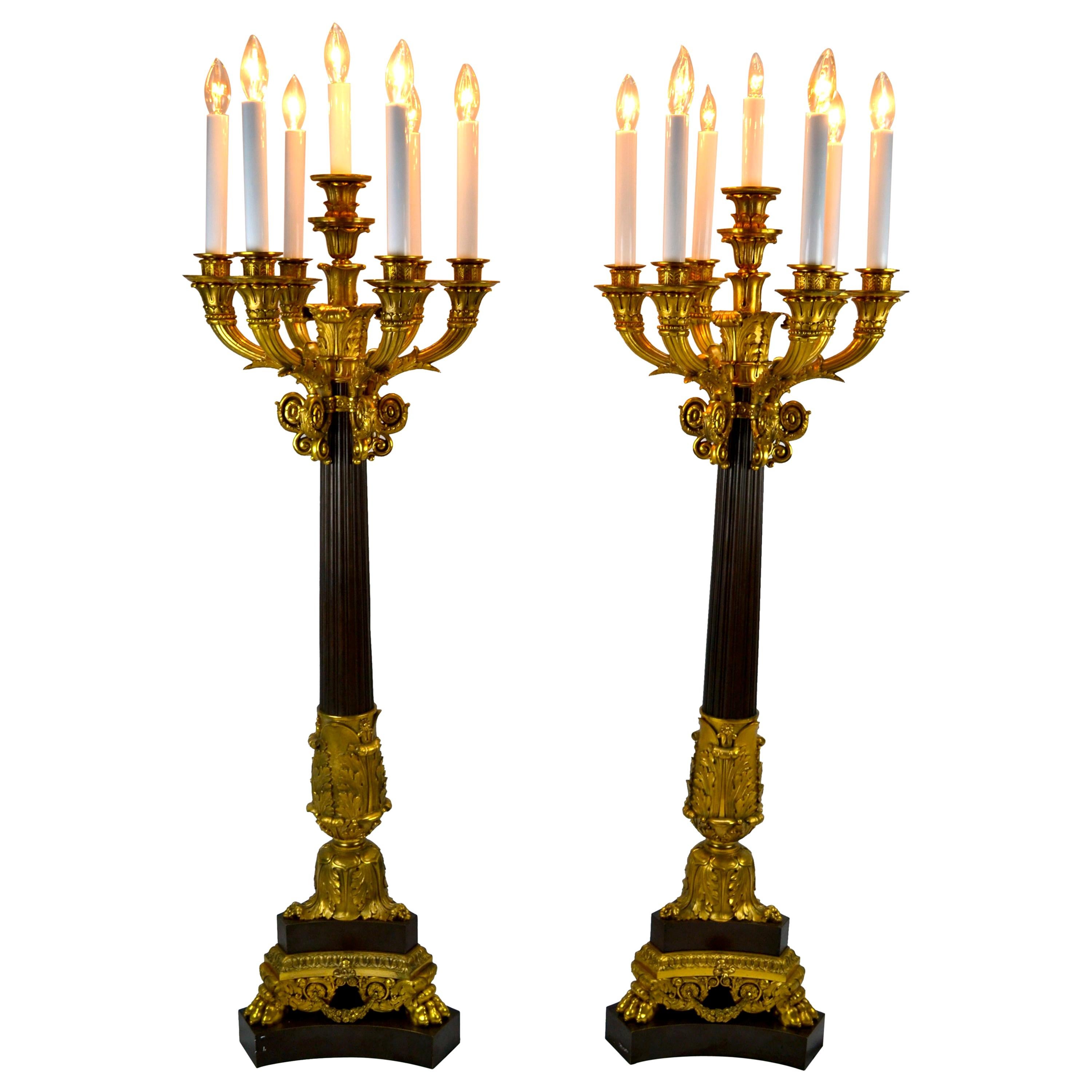 A very large scale pair of gilded and patinated bronze candelabra in the late French Restauration / Napoleon III style. The tapered central shaft decorated on the top and bottom in gilded bronze sits on a tri-form patinated and gilded bronze base