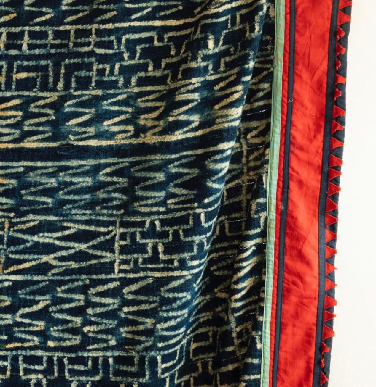 A very large scale N’dop display cloth panel made of strips of indigo dyed mixed fibre cloth tie dyed with typical designs. With the original red and green sawtooth border.

Bamileke, Cameroon c. 1950’s.