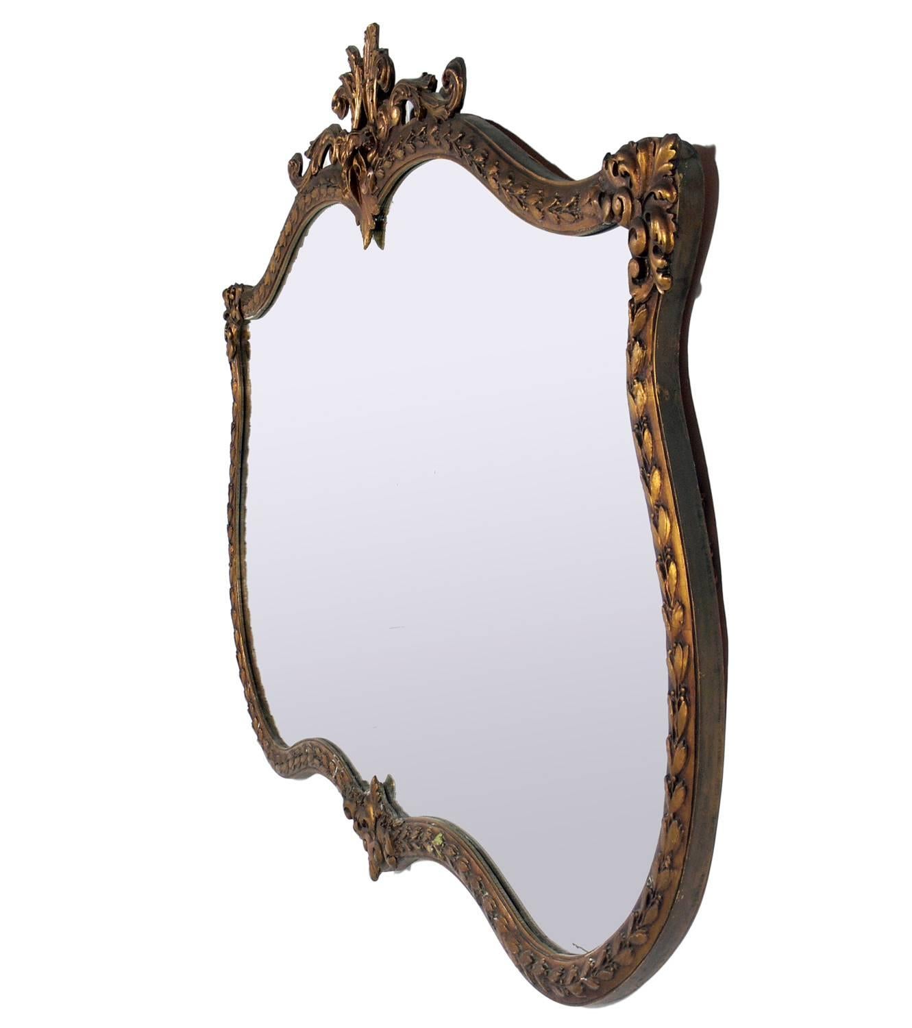 Large-scale ornate gilt mirror, American, circa 1940s, possibly earlier. It measures an impressive 5.5 feet width x 4 feet height approx. Retains warm original patina to both mirror and frame.