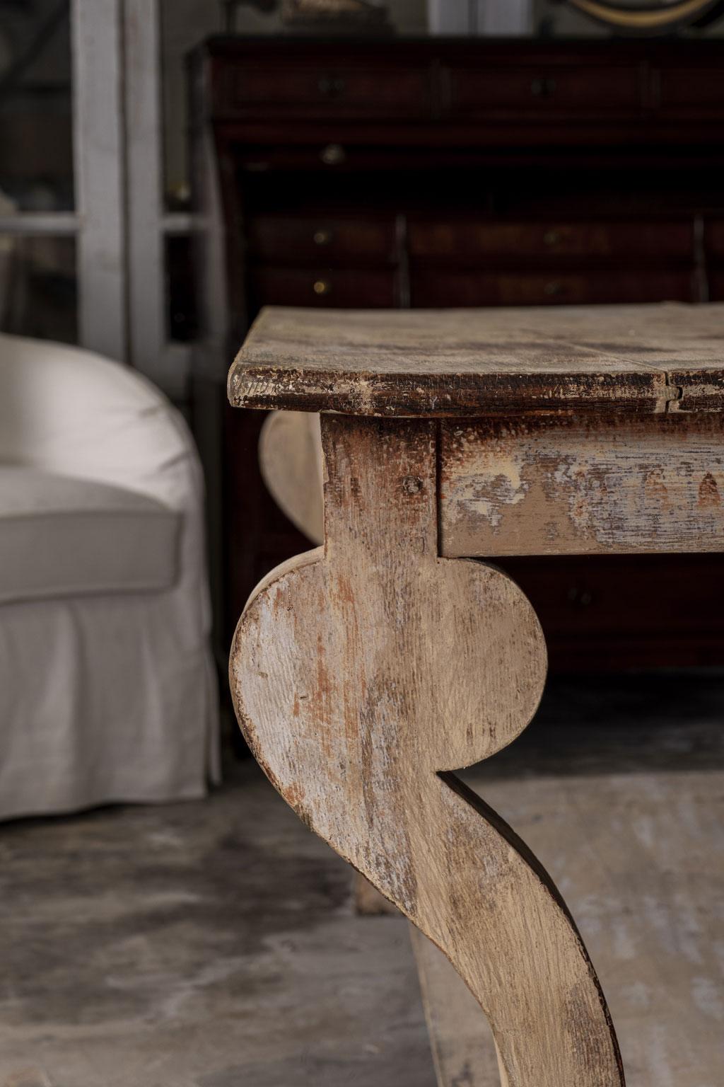 Large-scale painted console table, designed in neoclassical style. Large-scale long console, with a full-length under-shelf and hoof-shaped front feet. Remnants of early paint decorate console's scraped back surface. Measures 29 inches high x 71.5