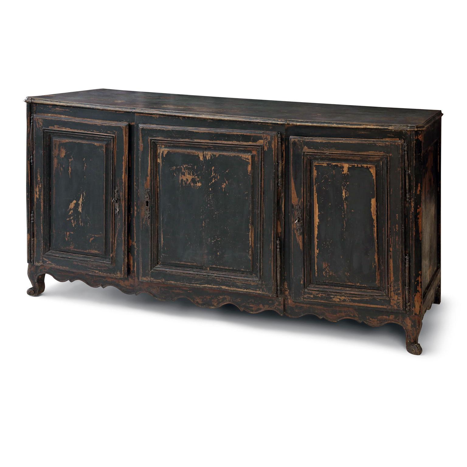 Large enfilade painted in black with dark blue undertones and hand carved in French walnut. Transitional Louis XVI-XVI style body raised upon cabriole legs with scalloped lower apron. Two doors conceal interior storage with one shelf and two half