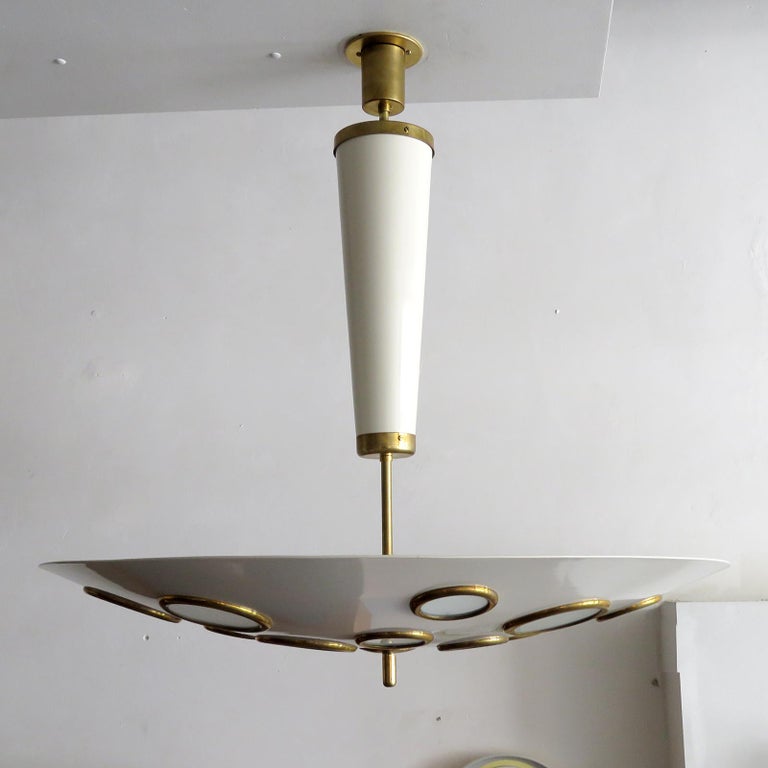 Stunning Italian pendant light by Lumen Milano, 1950 in brass and egg shell colored enameled metal, the large scale suspended circular shade is perforated with brass rimmed frosted glass diffusers of various sizes, wired for US standards or European