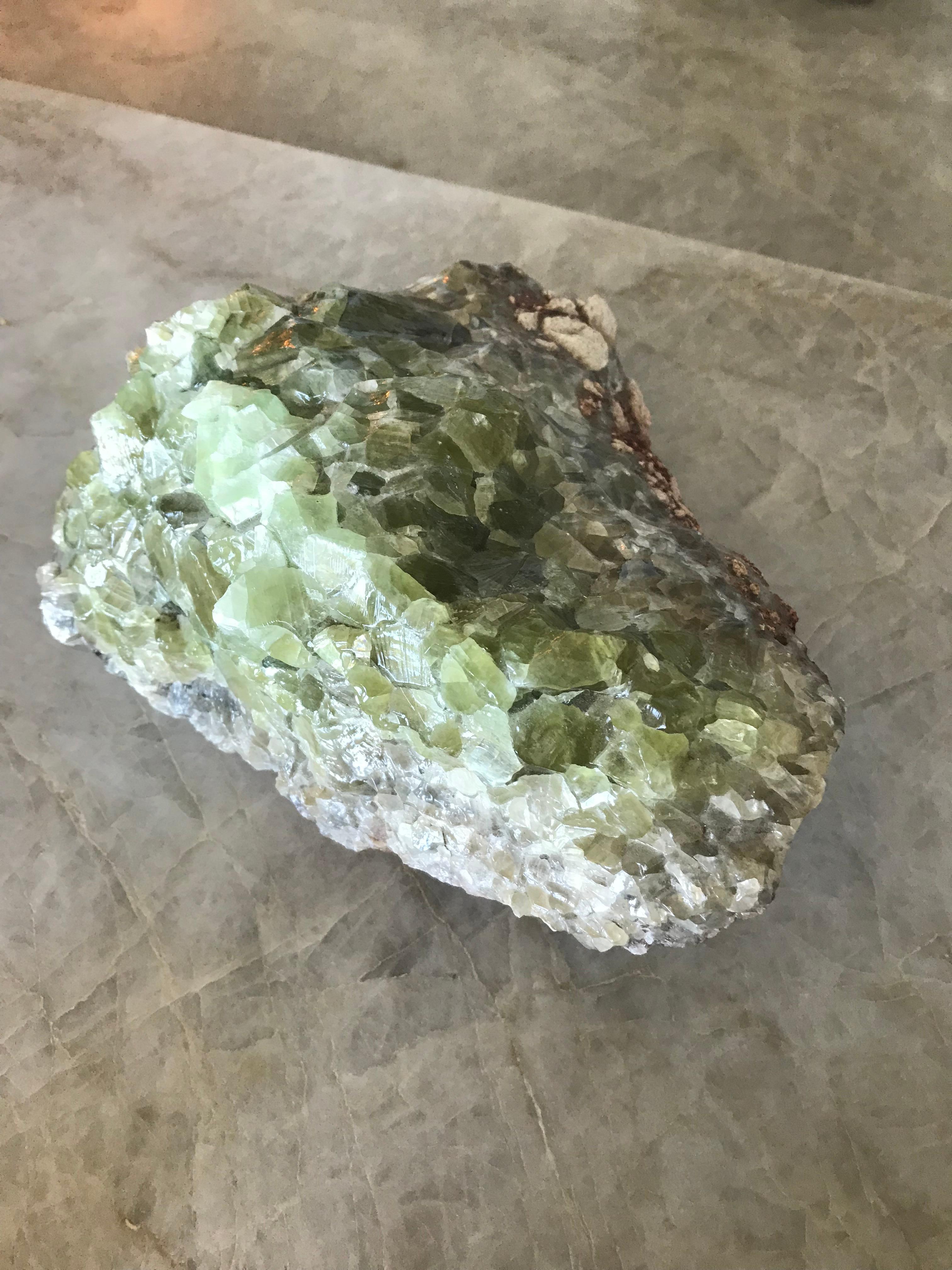Large scale peridot cluster with natural greens, white and deep purple colors.