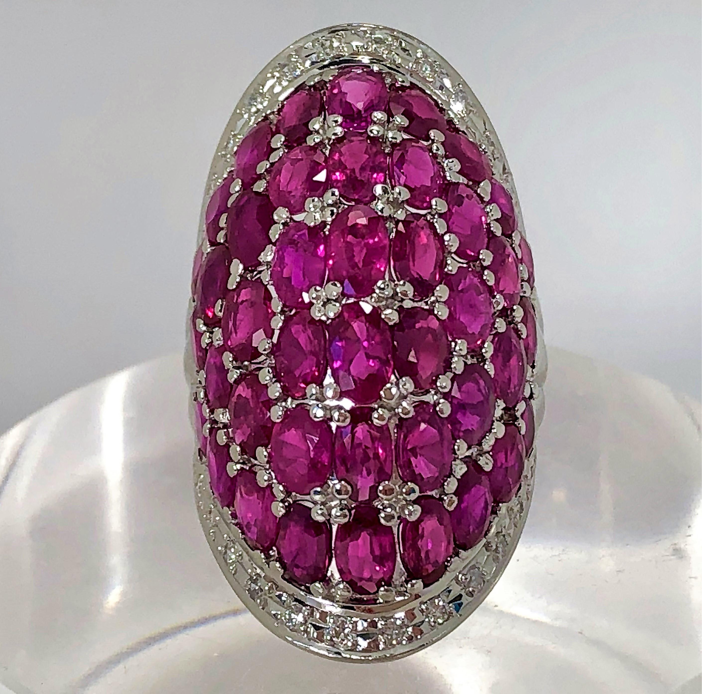 A beautifully contoured platinum ring set with assorted oval, faceted rubies weighing a combined weight of approximately 12.33 carats with even saturation and  medium tone. Accenting the ruby are assorted round brilliant cut diamonds weighing 0.24ct