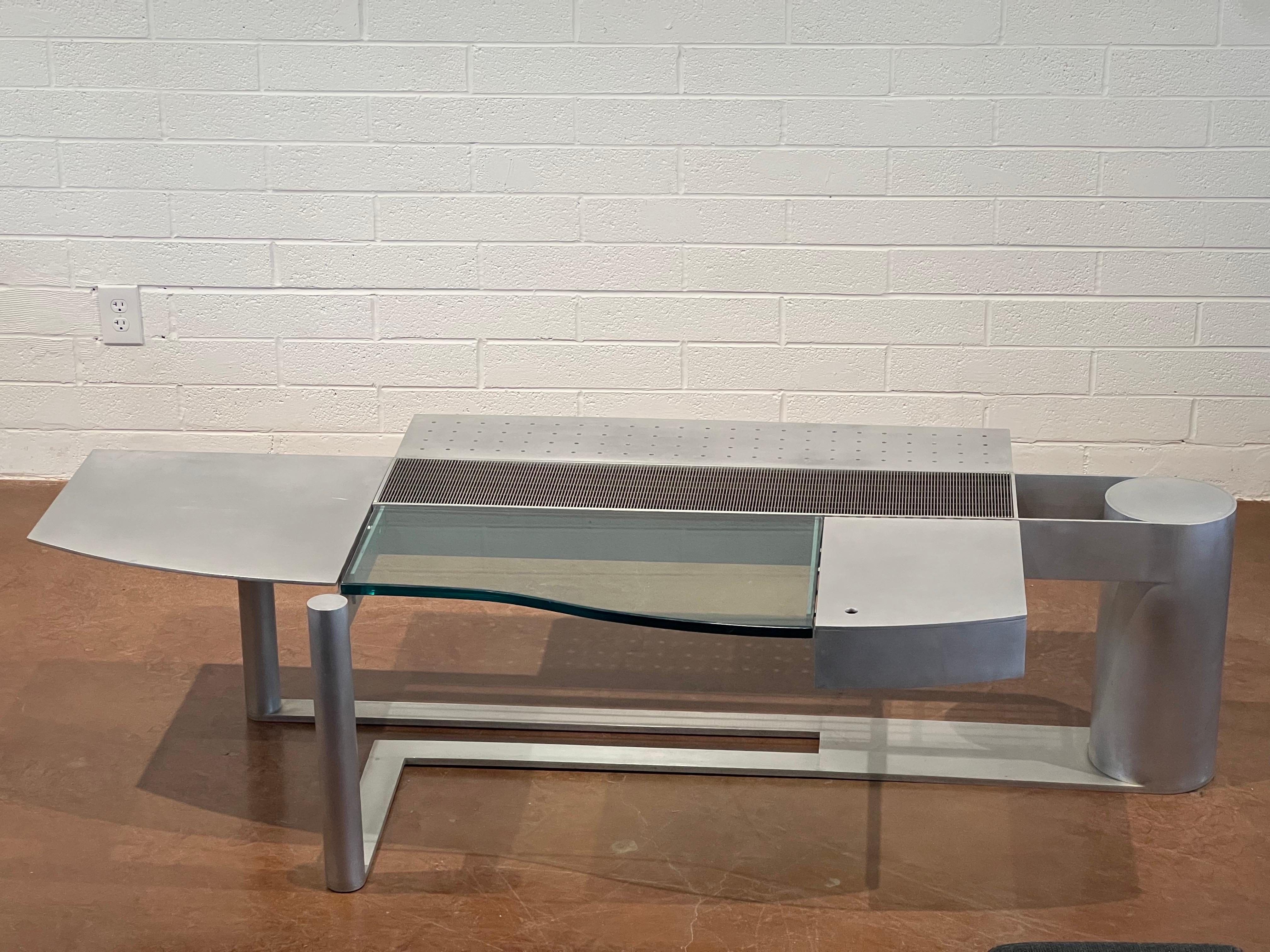 This large-scale coffee table, designed by the esteemed architect Robert Whitton, is a stunning example of craftsmanship and design excellence from the late 20th century. Constructed from aluminum and glass, the table showcases a perfect balance of