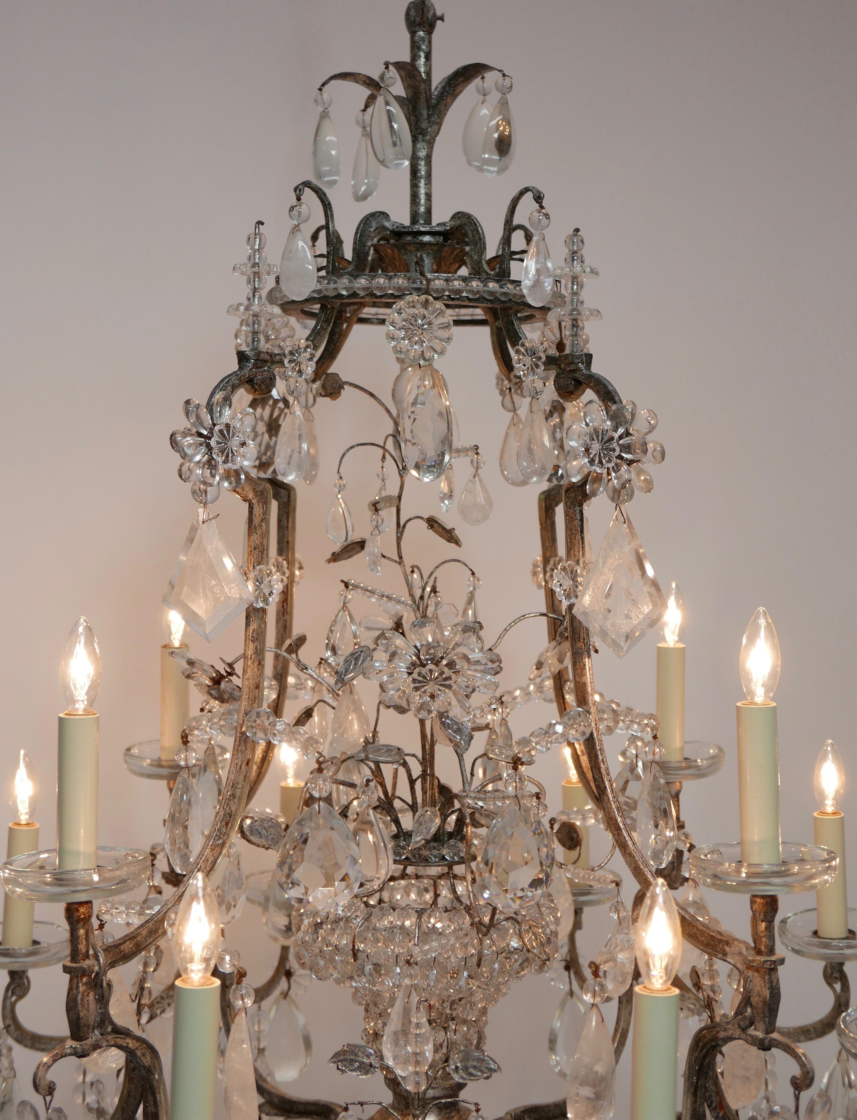 Exceptionnel lustre à 12 lumières en cristal de roche et prisme de verre, probablement de l'emblématique Maison Baguès à Paris. La cage (cadre) en fer forgé est recouverte de feuilles d'argent. Il s'agissait à l'origine d'un luminaire à bougies, qui