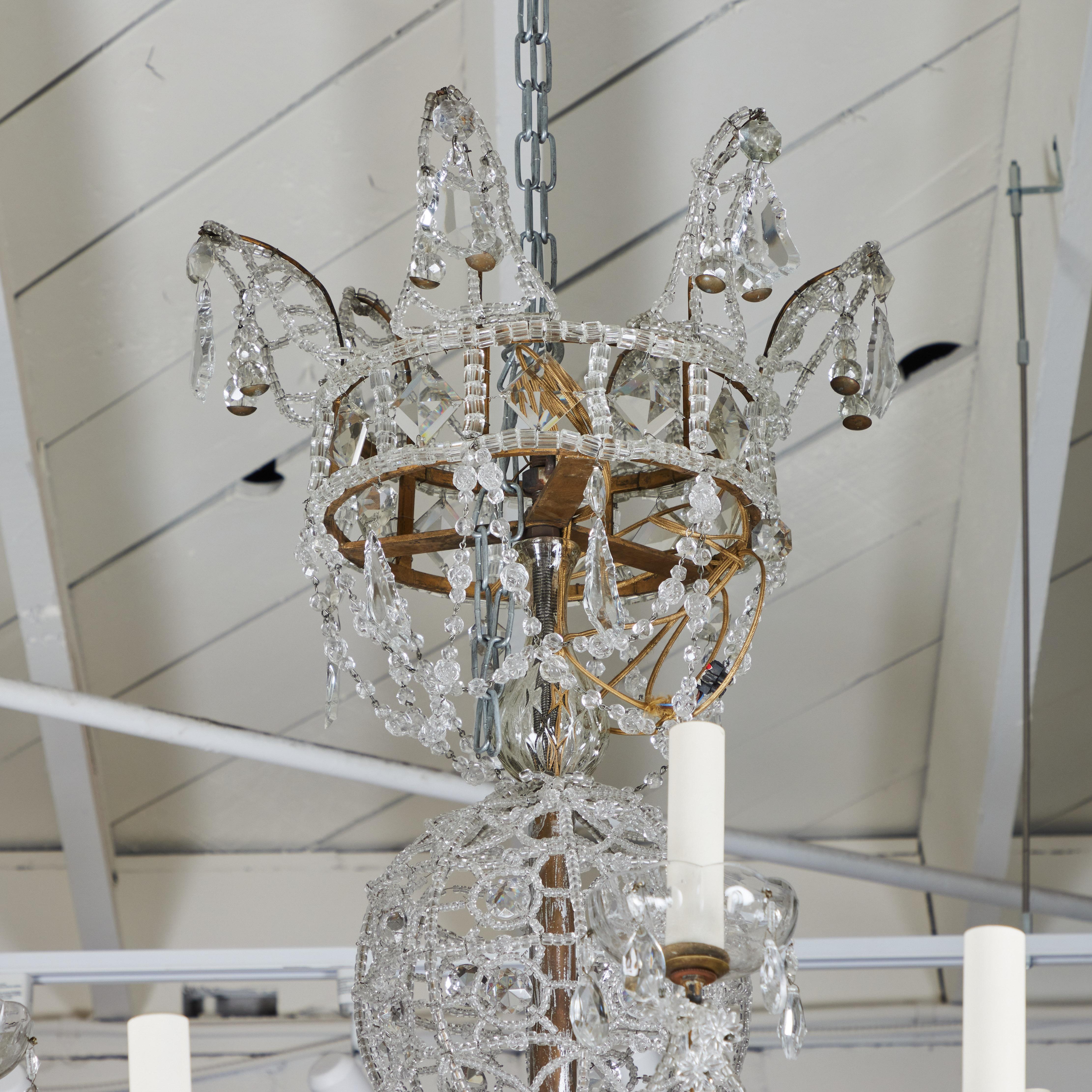 A stunning, large, beaded crystal chandelier with scalloped placards and spheres. The arms are gilded metal and the shaft with sphere shapes terminates in a gilt-wood floret and large crystal orb.  Crystal bobeches with tear drops.  18 lights.  From