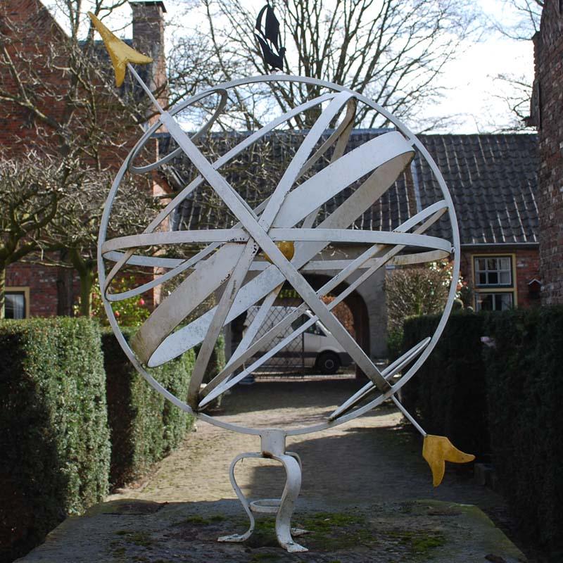 A beautiful large scale is armillary in metal with a central sphere depicting earth. 
The arrow is the axis, the earth revolves on. The point, earth, and arrow are gold leaf gilt. The armillary further features the horizon, the ecliptic, both