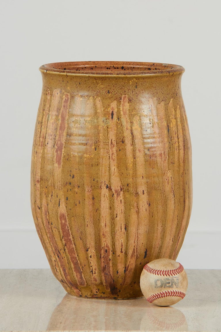 A large, tan and green and reddish-brown studio ceramic vessel featuring a horizontal linear pattern on the exterior and speckled interior. This vessel would make a great entry way vase.

Dimensions: 9” diameter x 14” height

Condition: