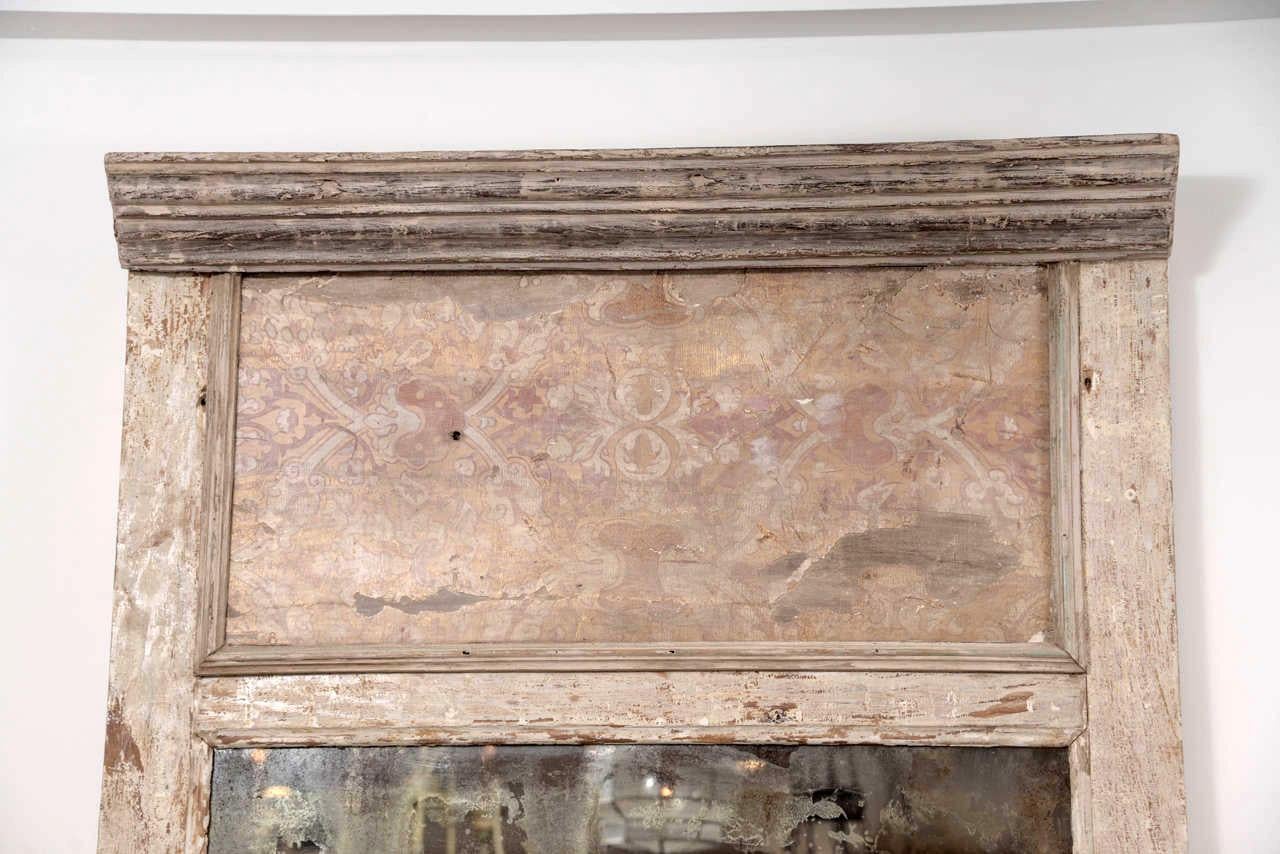 Large-scale trumeau style white-painted mirror: large architectural paneled mirror from early 18th century (or earlier) Italian large architectural wall panel fitted with later mirror. Trumeau mirror is decorated in layers of early paint. Remnant of