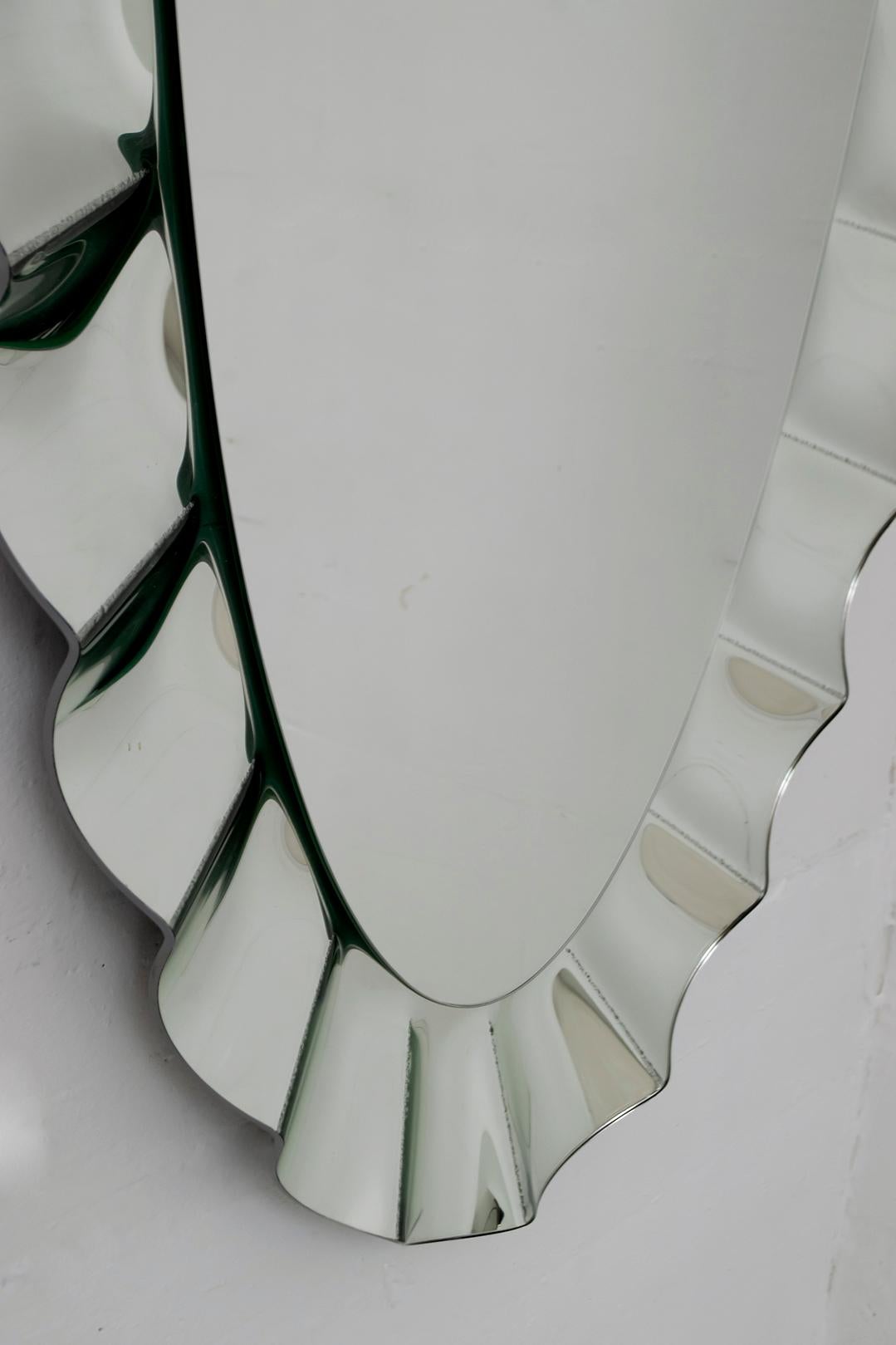 Imposant miroir ovale encadré par un plus grand miroir ondulé. Le panneau arrière comporte un insert pour la suspension verticale et horizontale. Matériaux et fabrication de qualité supérieure