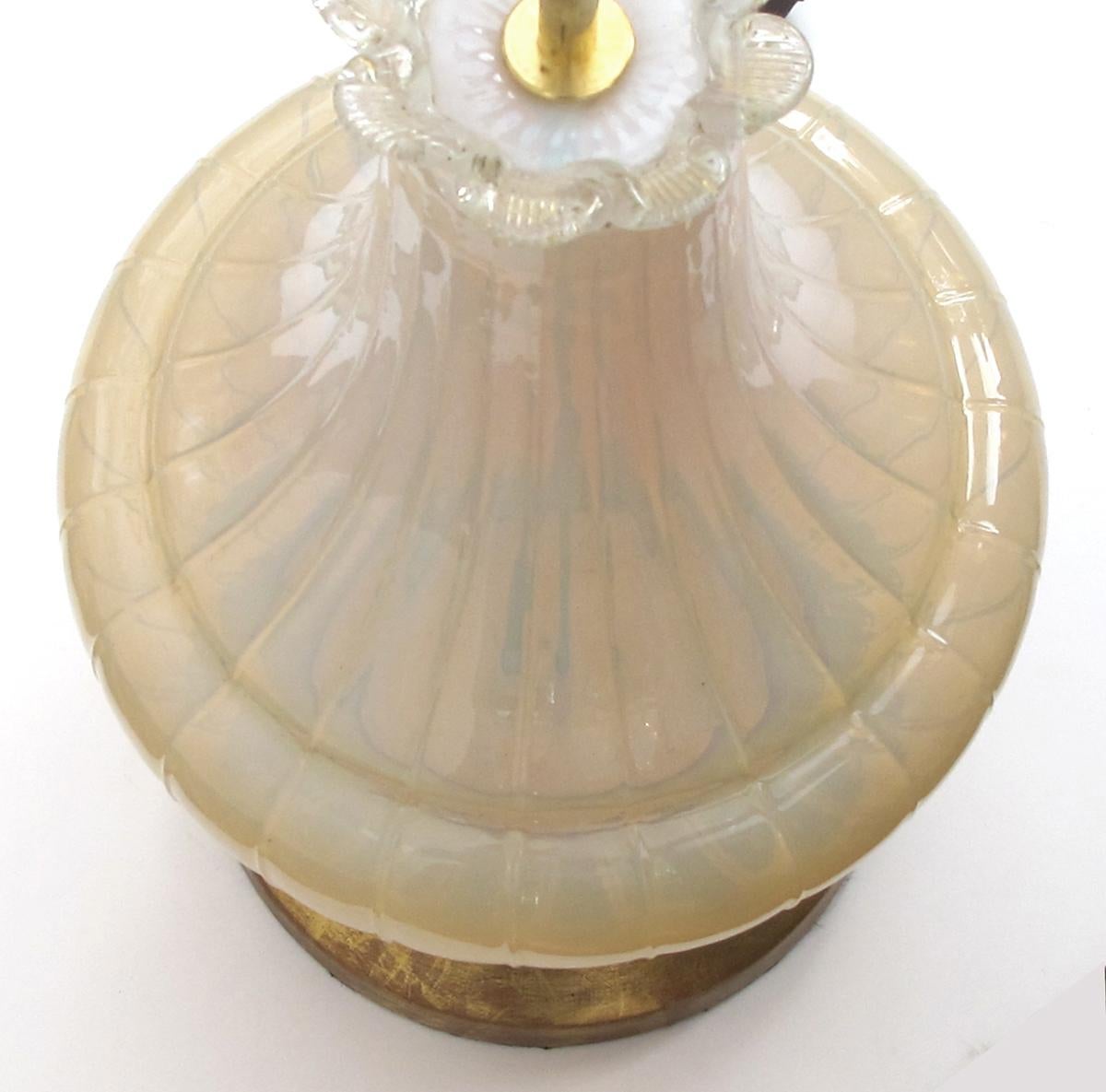 The hand blown lamp with long sweeping neck above a bulbous body all in a soft translucent pale yellow glass.