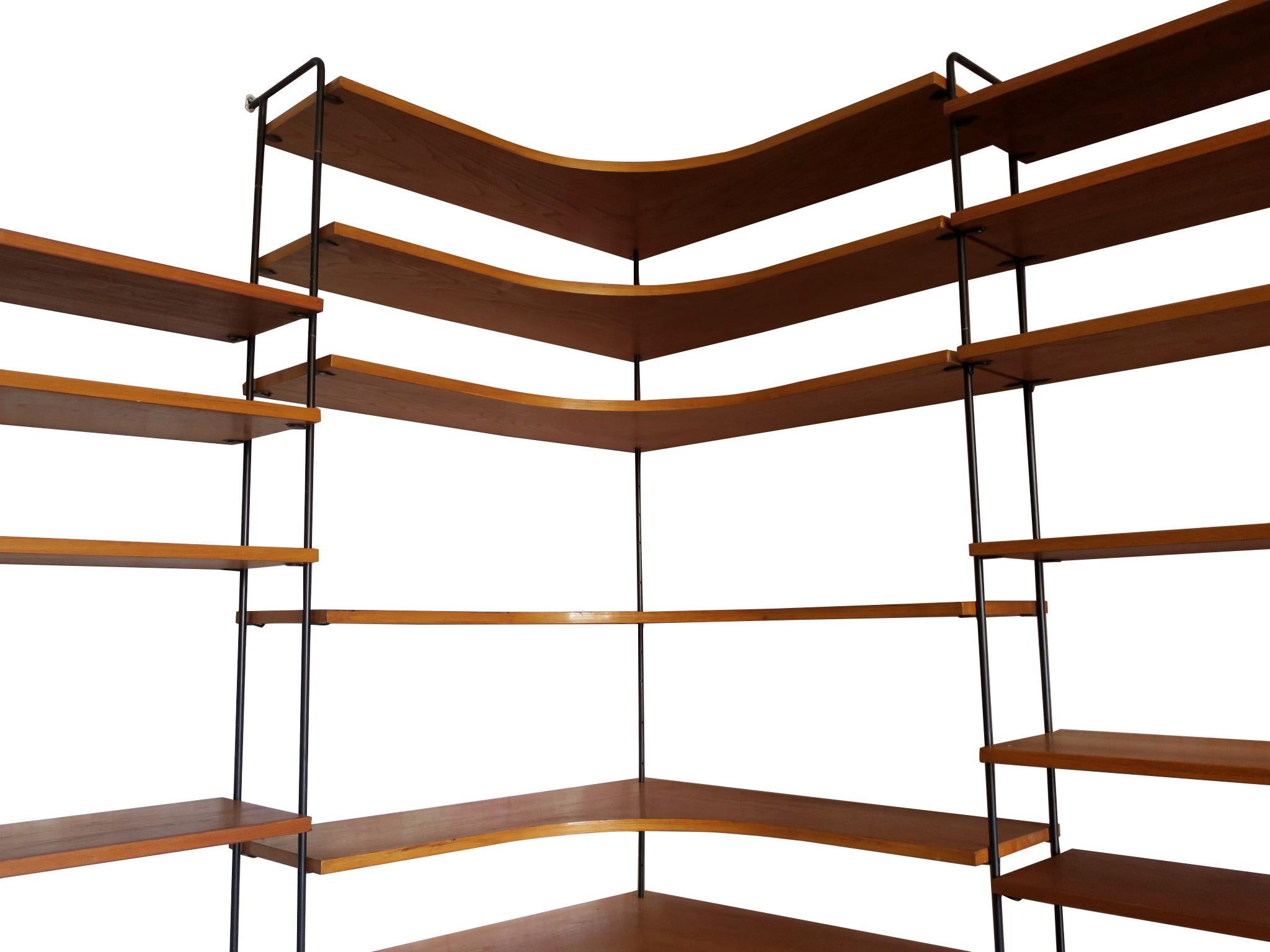 Fine Scandinavian modular wall shelf system on slender black metal supports, stabilized by wall screws. The shelves can be hung at will, held by small metal hooked pegs placed in the numerous small holes in the metal supports, a simple and elegant