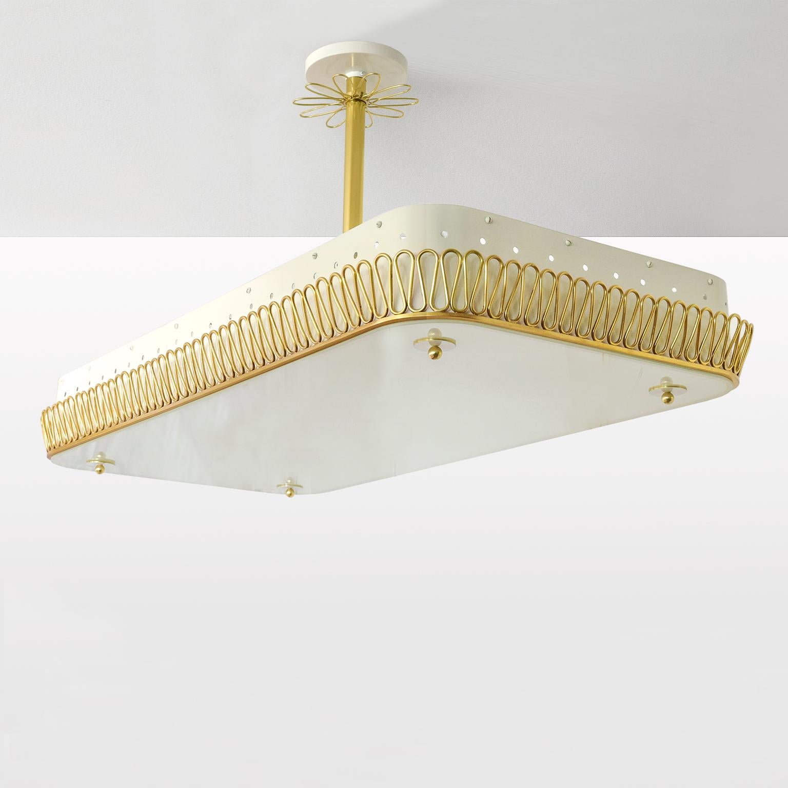A large rounded corner rectangular Scandinavian Modern pendant with a lacquered cream white body which has a polished brass filigree design along its bottom edge. A large opaline glass panel is attached by brass hardware. Polished brass stem and