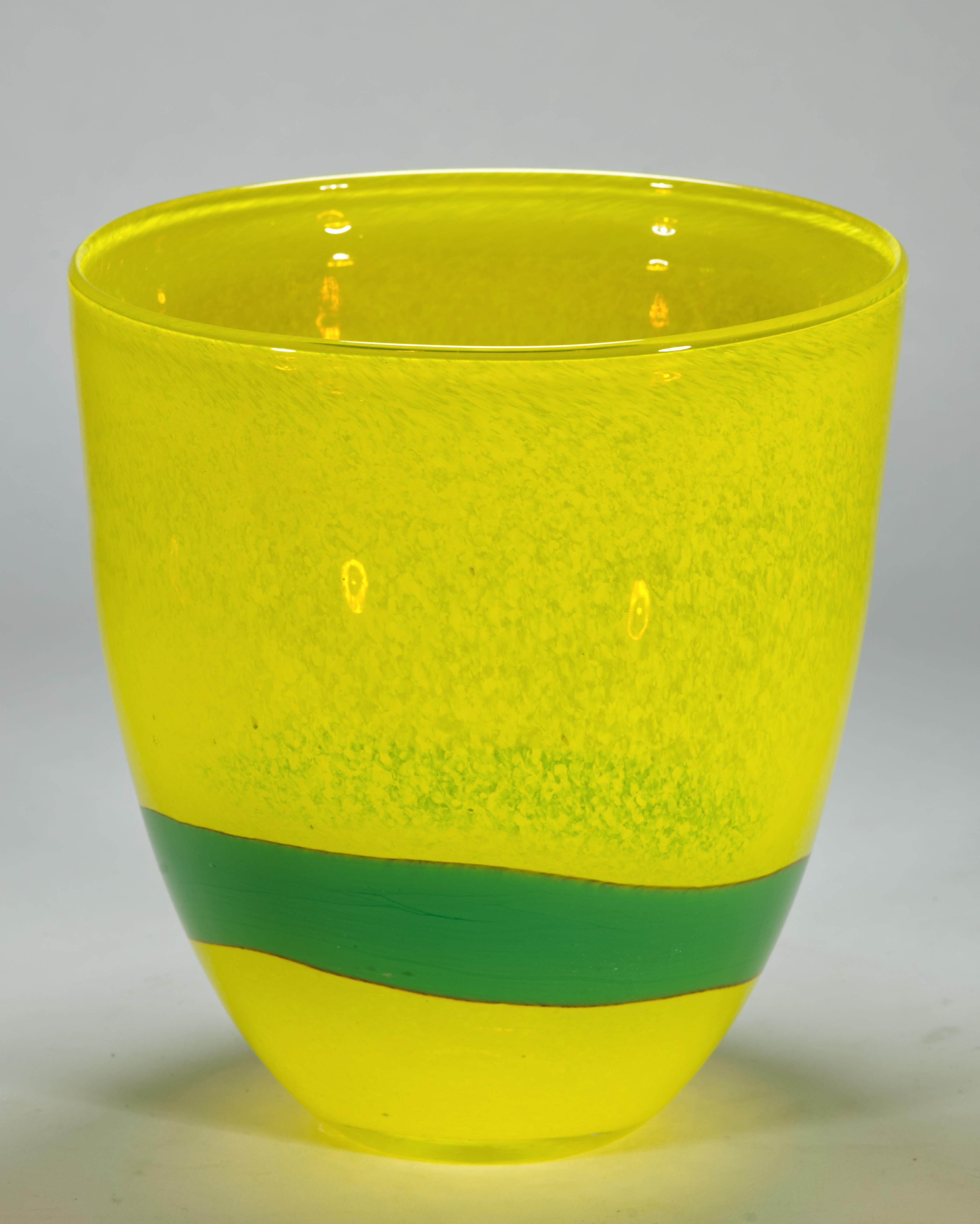  Cet étonnant vase sculptural est décoré d'une bande tourbillonnante de verre fusionné vert, qui entoure la pièce de manière libre et guide le regard le long des courbes du vase. La couleur jaune tachetée semi-transparente du verre apporte un éclat