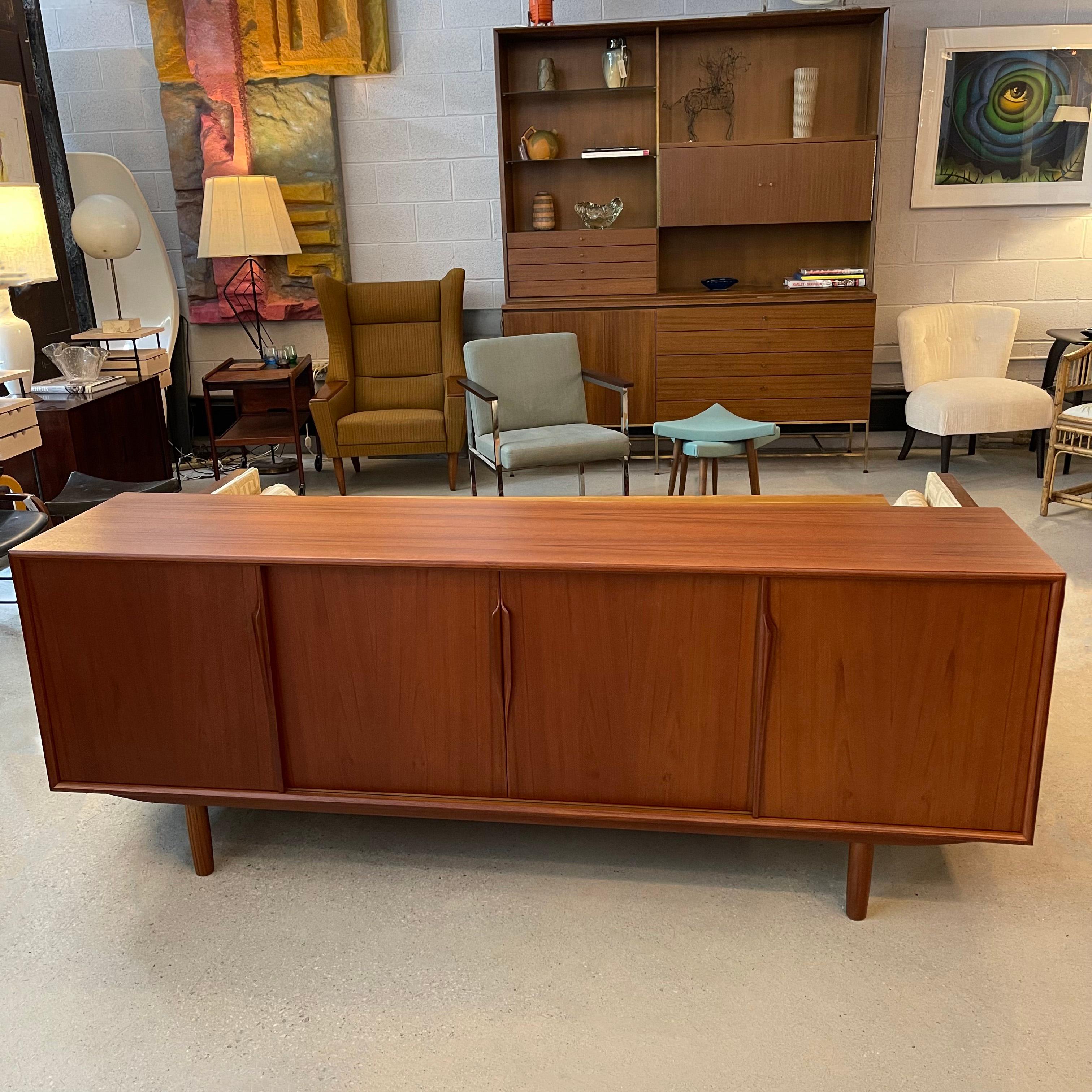 Own a piece of streamlined Scandinavian design with this teak Danish Modern credenza by Gunni Omann for Axel Christensen Odder Mobler. The credenza provides ample storage with sliding teak doors with sculpted handles that open to reveal three