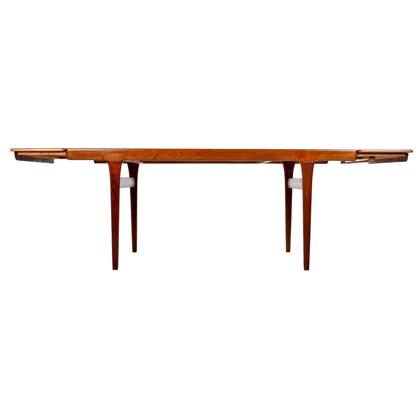 This large dining table stands firm in its solid pine core covered with a teak veneer. This hefty beauty boasts solid teak legs and gorgeous edge banding. The opposing wood grain on the leafs enhance the simple and Minimalist nature of this this