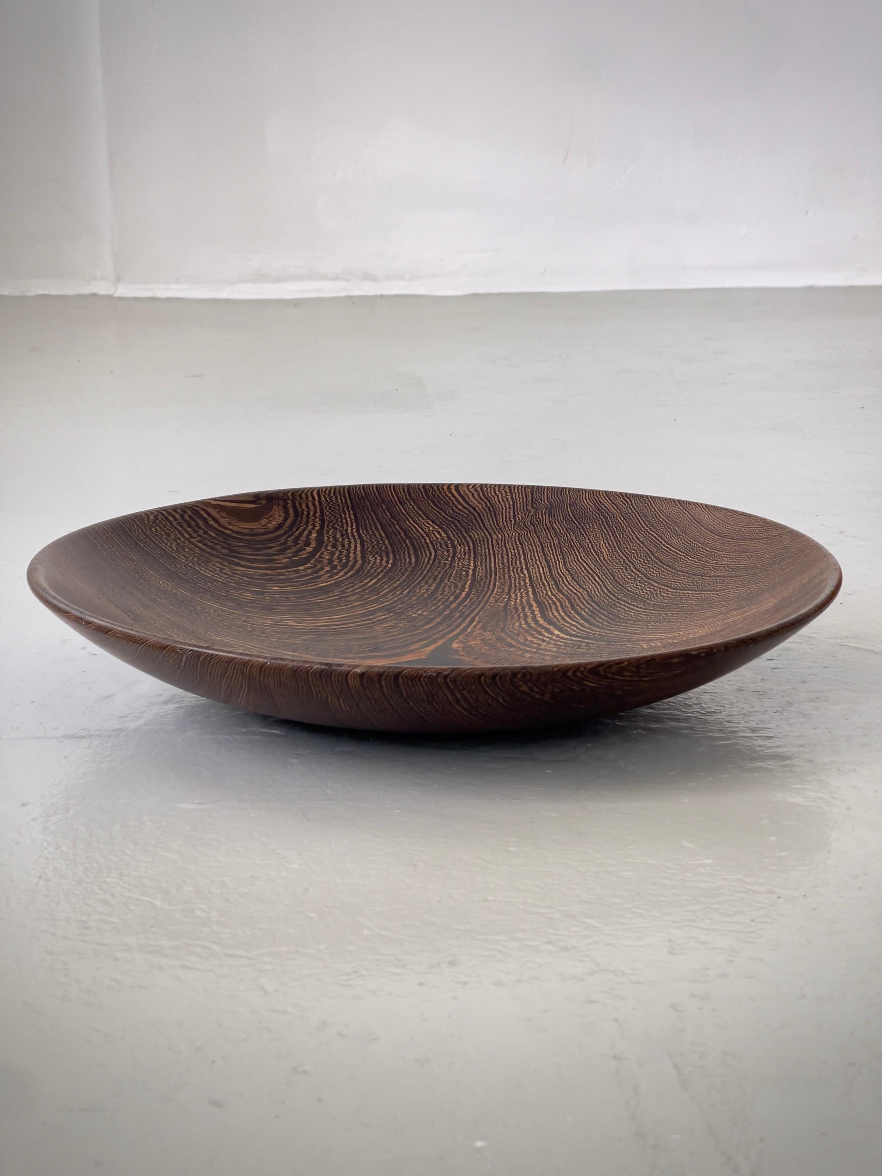 Ce grand bol de service scandinave, sculpté à la main dans du bois dur foncé en Finlande dans les années 1960, est un exemple convaincant de design moderniste nordique ancré dans la matérialité naturelle et la tradition artisanale. Sa forme