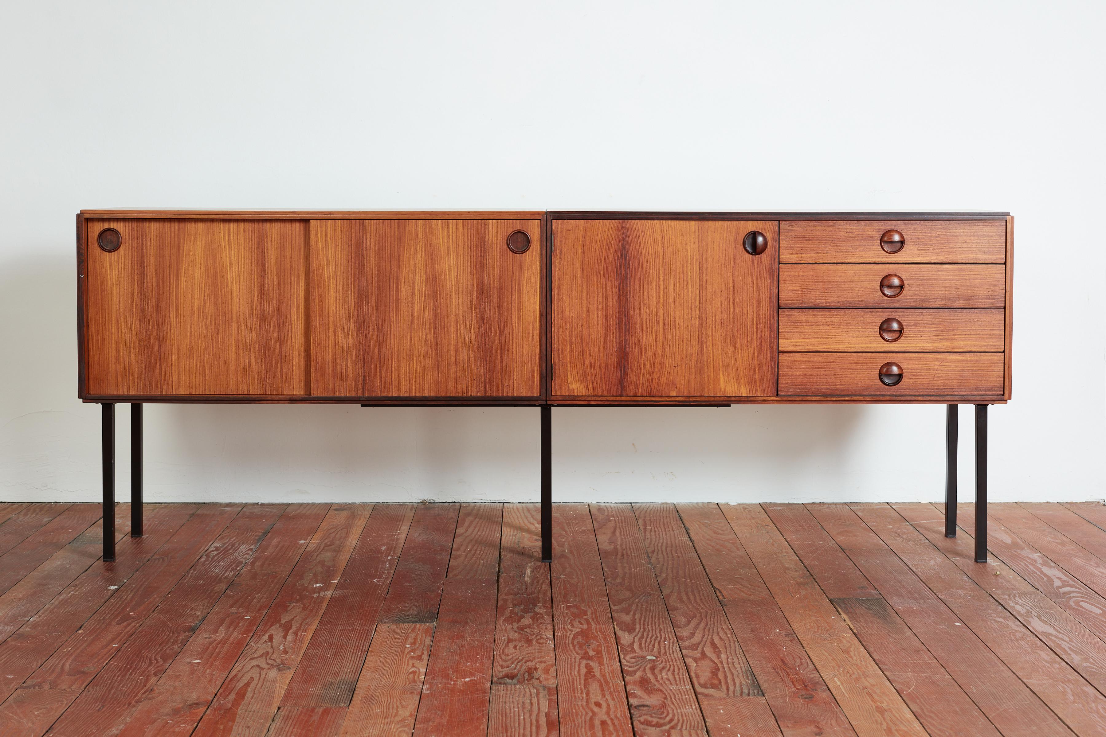 Handsome Danish sideboard constructed of teak with rosewood pulls and black iron base.
Beautiful craftsmanship and patina 
Sliding cabinets doors that open up to shelving with set of 4 drawers resting on sleek iron base. 

Denmark 1950s