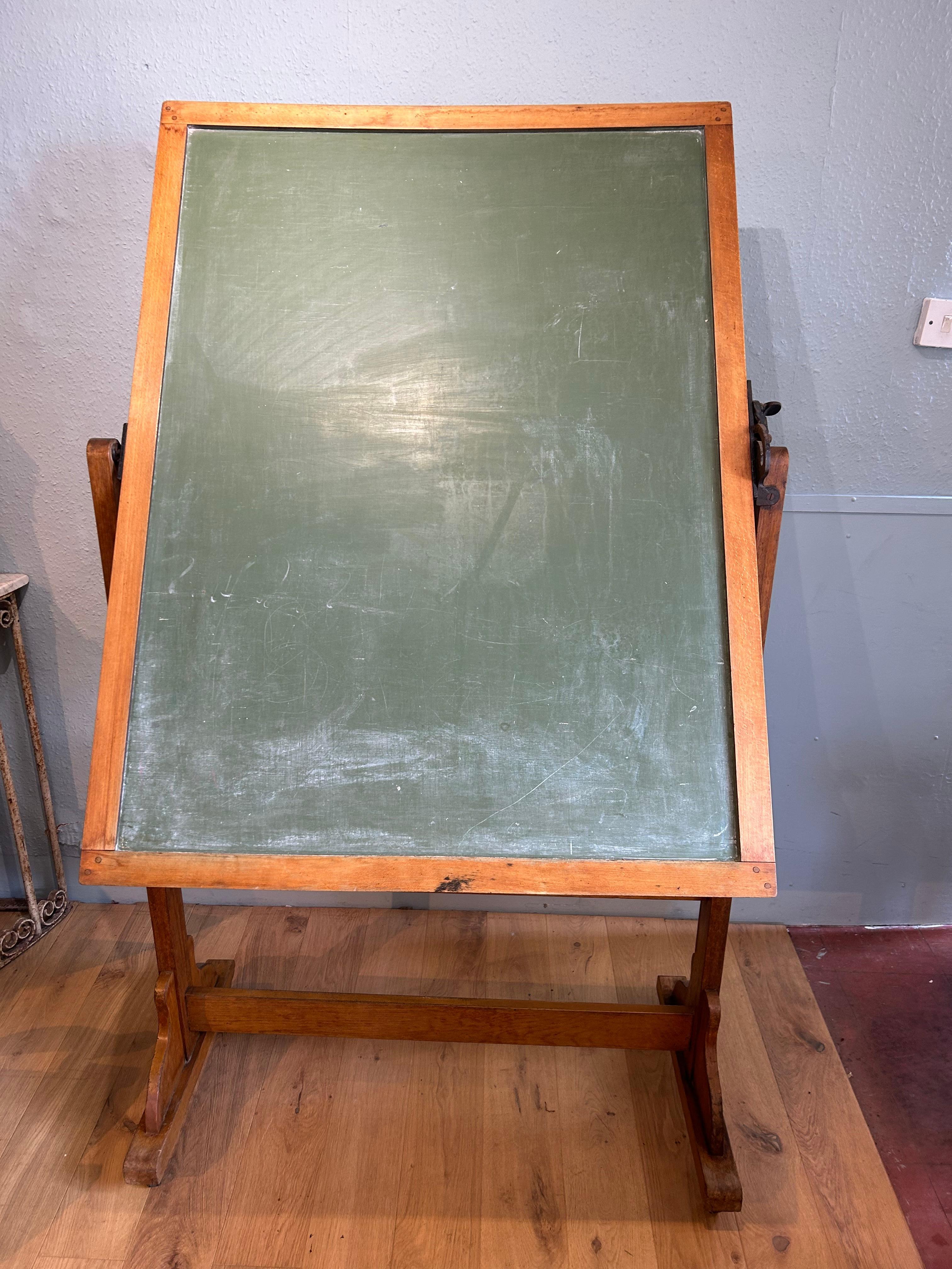 An attractive large English school blackboard, circa 1940, constructed in beech & teak. This double sided blackboard has an adjustable cast iron screw clamp to the one side, enabling the board to be tilted to whatever position is required.