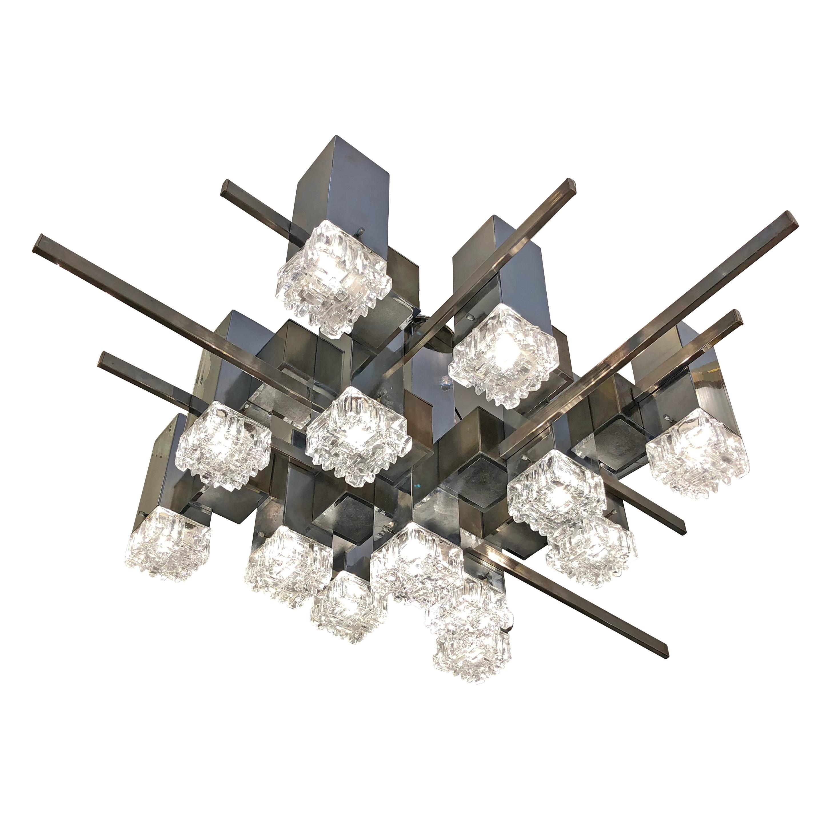 Large chandelier designed by Gaetano Sciolari in the 1960s featuring an “abstract” frame with nickel, brass and plastic components and textured glass shades. Holds 13 candelabra sockets. Height can be adjusted as needed by adding a