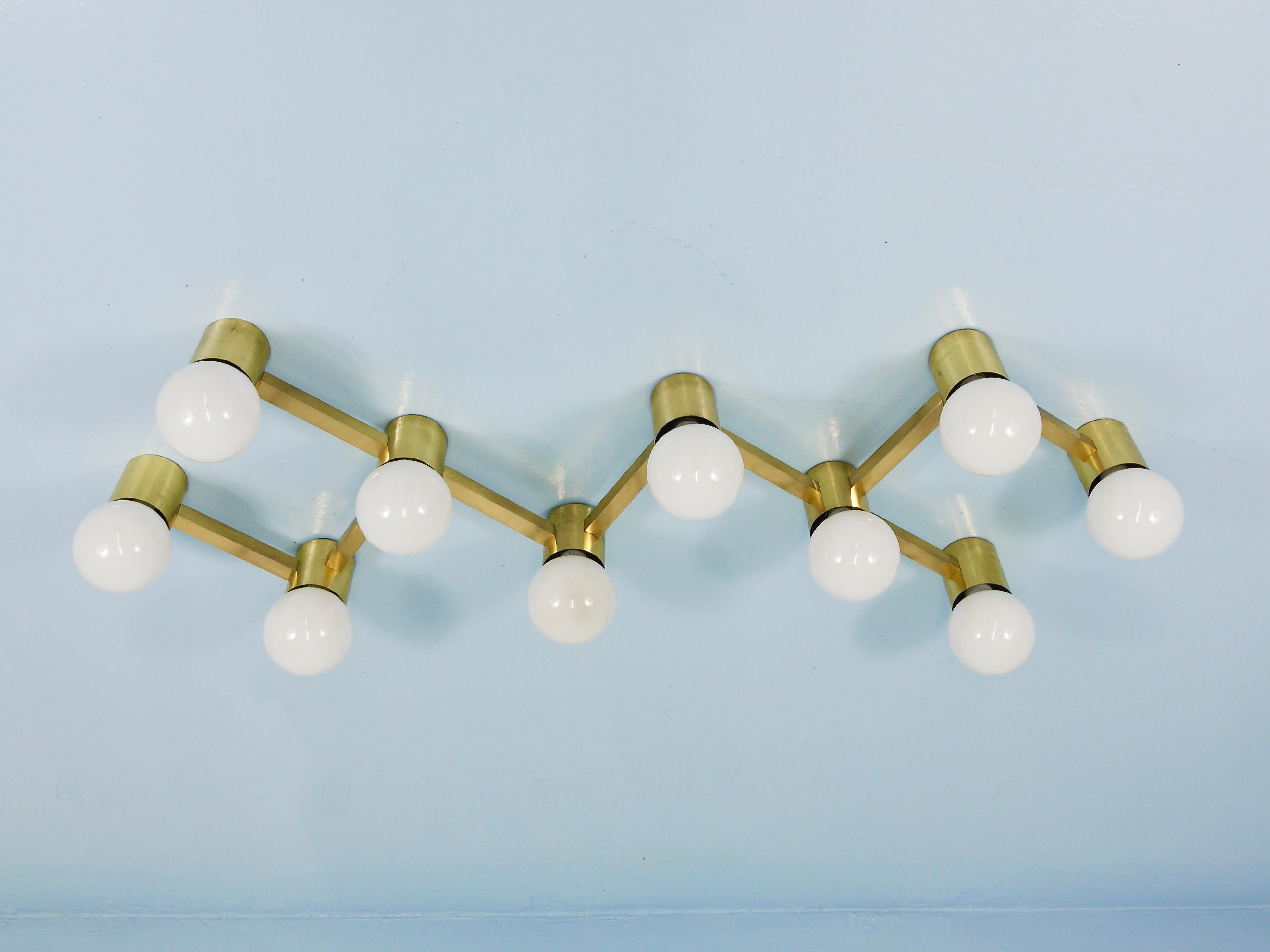 Eine auffällige Lichtskulptur aus den 1970er Jahren, die sich sowohl als deckenbündiger Kronleuchter als auch als Wandleuchter eignet. Dieses beeindruckende Stück aus Messing verfügt über zehn Lichtquellen und zeigt den typischen skulpturalen