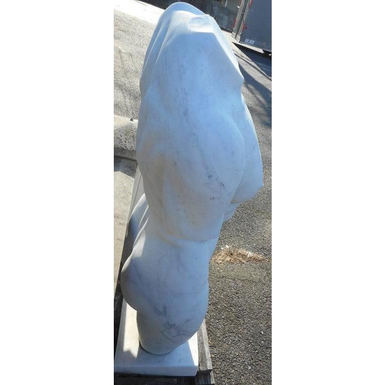 This impressive statue of a nude male torso is made of solid white marble and sits on top of a square block base. The elegant design shows intricate detail and quality craftsmanship. Incredibly solid and heavy, this piece is sure to make an