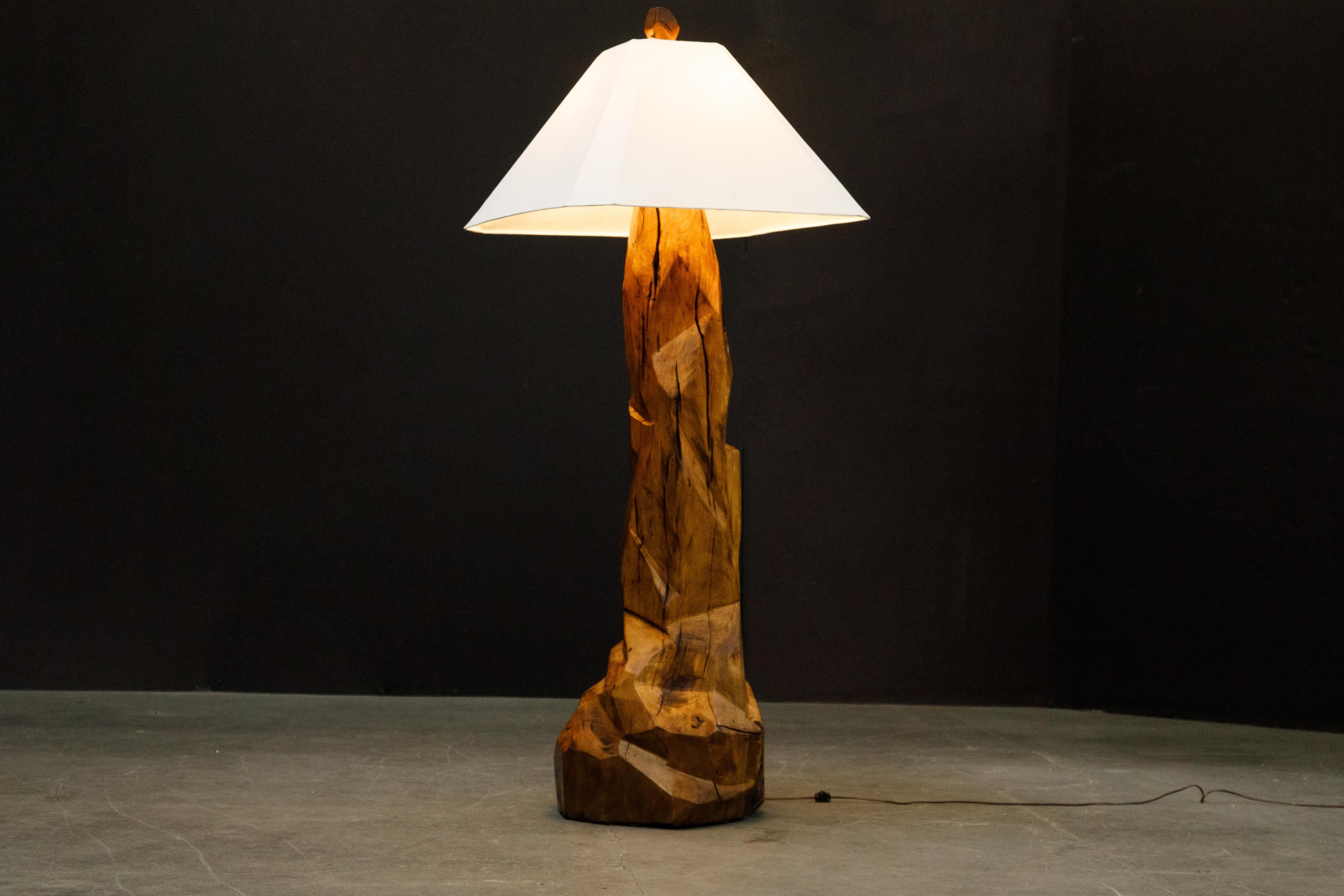 This monumental 1970s California Craftsman sculptural carved wood floor lamp is exquisitely crafted from a large slab of hardwood and polished for a smooth finish. The finial is carved from the same wood. For size comparison the lamp is shown in the