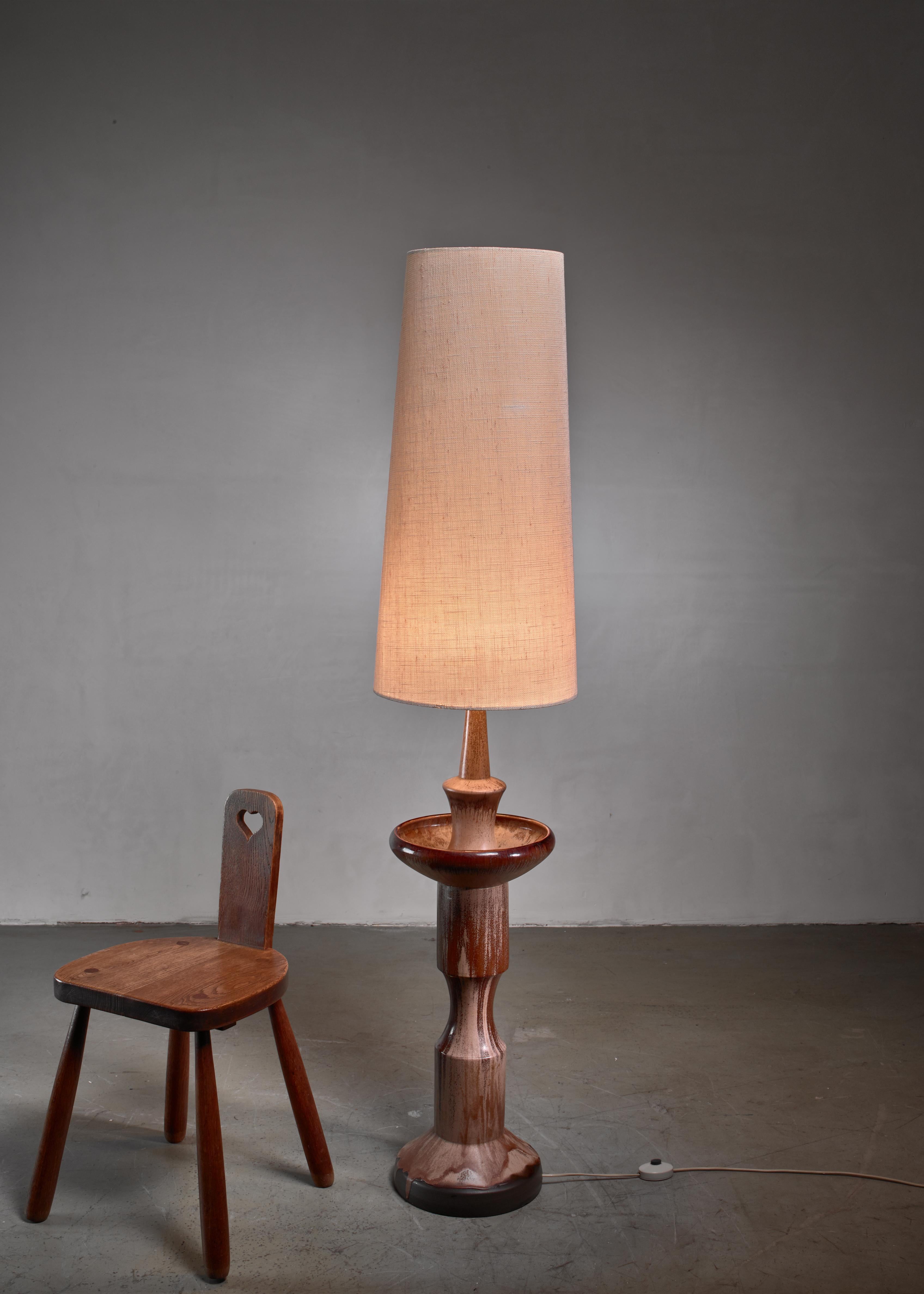 A large sculptural, Danish modern ceramic floor lamp with an earth tone glazing.

The measurements stated are of the lamp without a shade. The shade is newly made, other dimensions are available upon request.

       