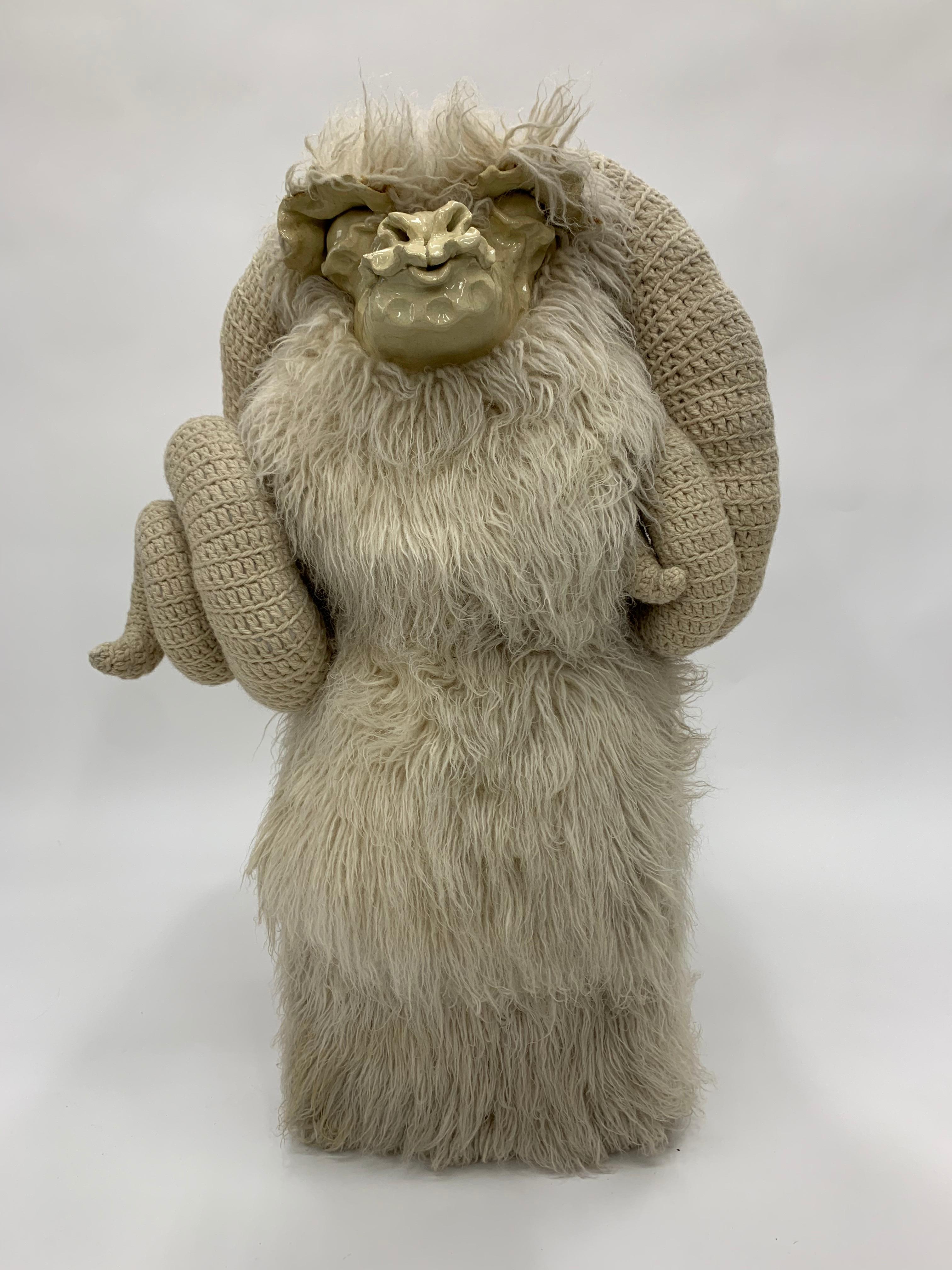 A  rare sculptured bench/ ottoman by artist Edna Cataldo. The artist utilized flocati wool, wood, and ceramic to create a truly unique ram. The face is sculpted ceramic fired with a glazed finish. The curling horns are hand crocheted.
Edna Cataldo