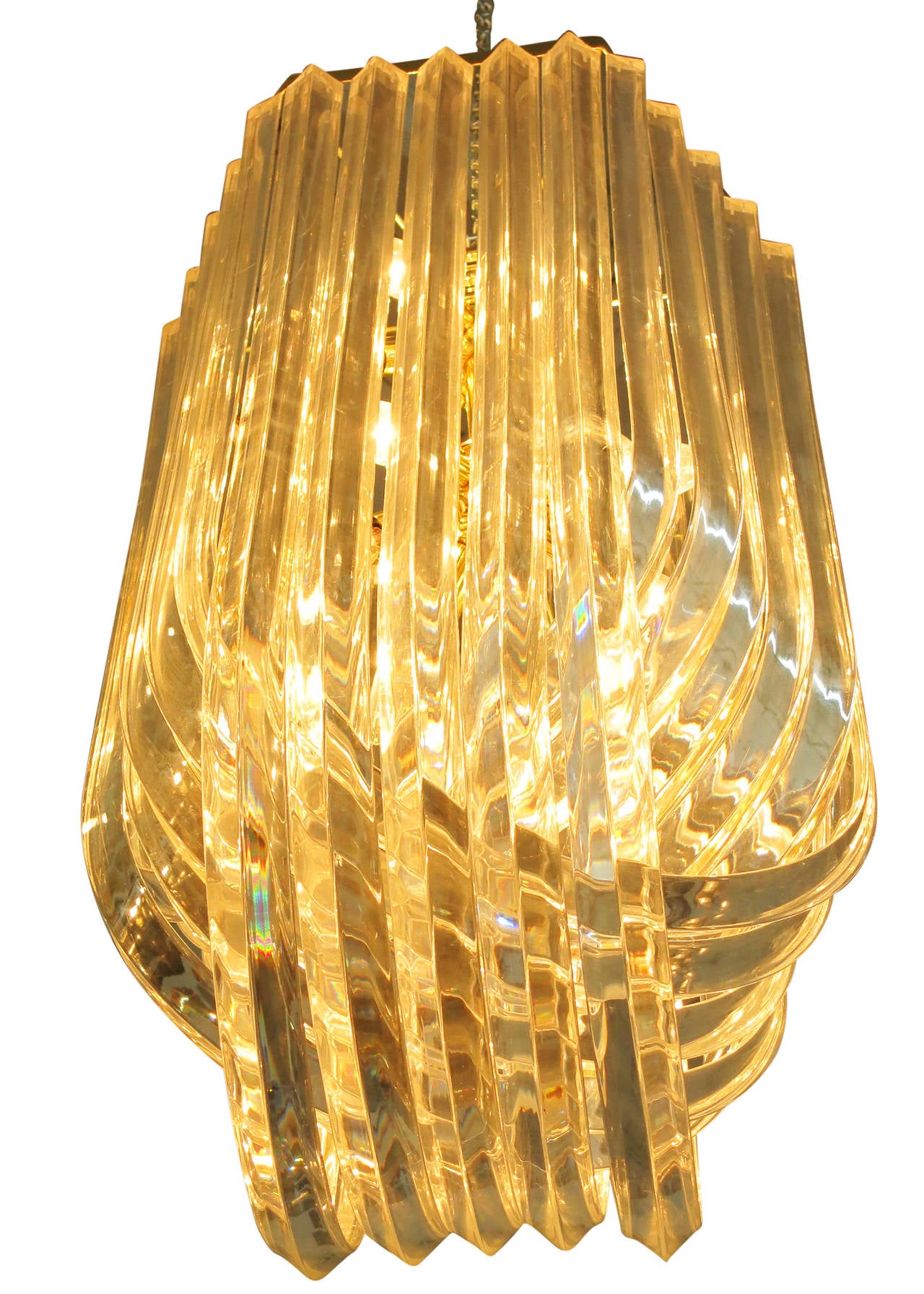 Made circa 1970, this Hollywood Regency inspired sculptural Lucite chandelier is comprised of three rows of twisted 2 inch thick Lucite ribbons of various sizing. These ribbons crisscross through each other while fixed to a brass frame.

 