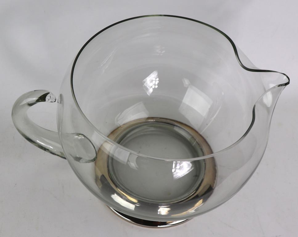 Unusual scale blown glass water pitcher on bright chrome base. Large glass bowl body (10 inch dia.) with applied glass handle. This example is in perfect condition, clean, original and ready to display and use.