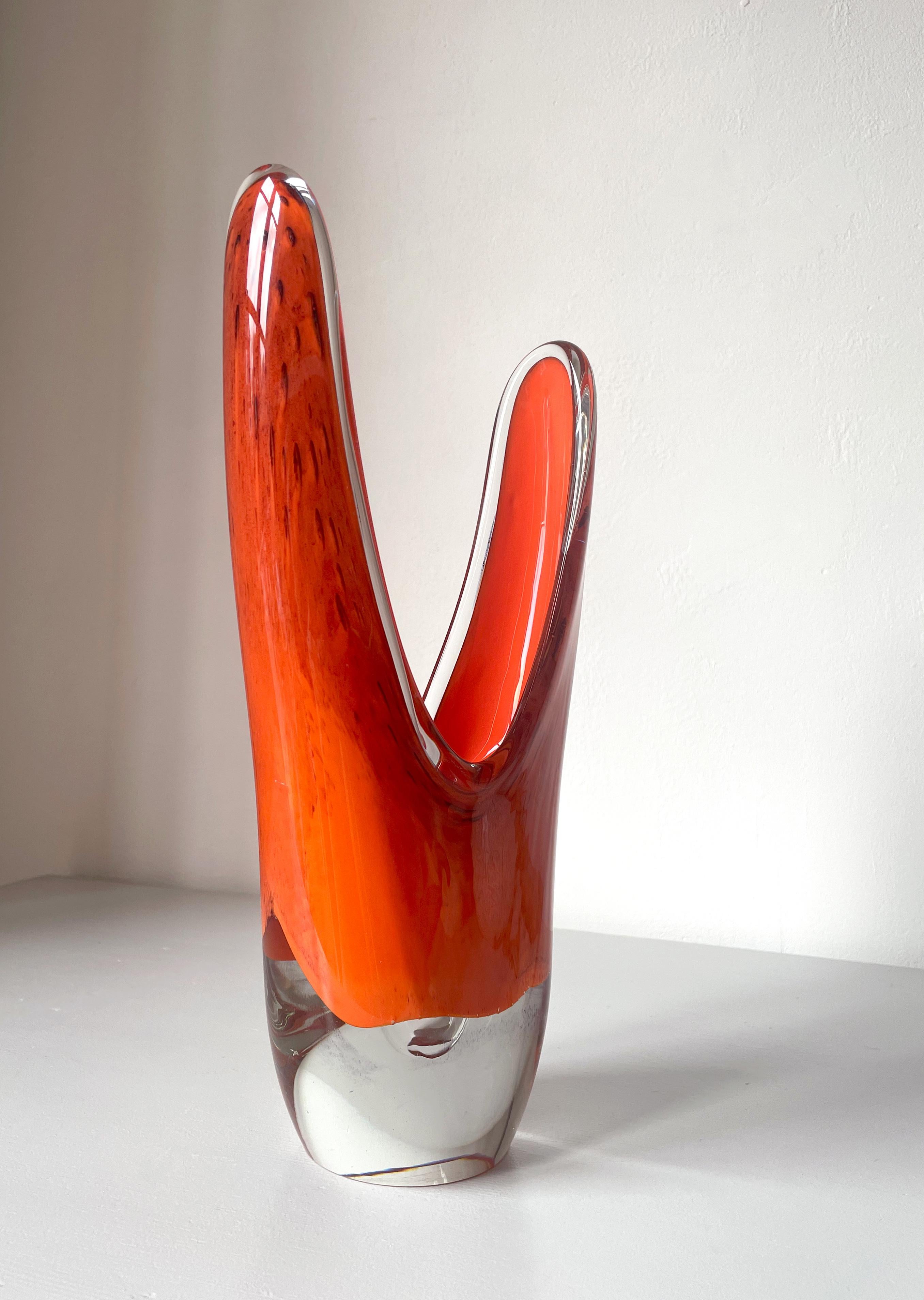 Sculptural asymmetrical mouth blown art glass vase. Encased deep orange glass with black accents and clear solid base. Scandinavian organic modern piece designed and handmade in the 1950s in the style of Flygsfors, Murano and Holmegaard. Beautiful