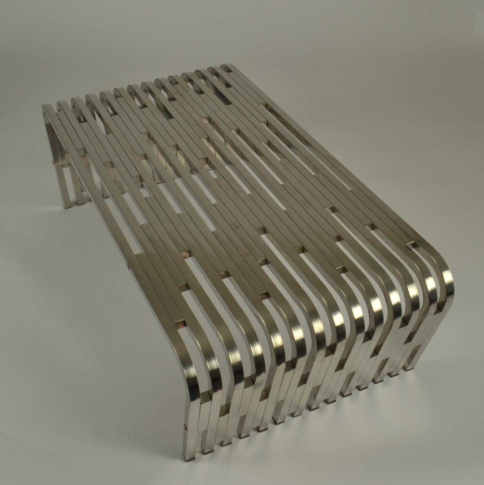 Large sculptural stainless steel coffee table is made out of extruded boxed stainless steel  segments. The steel is crafted into  different lengths, assembled and then riveted together to form this art table. The table is then bent into  a ‘U’