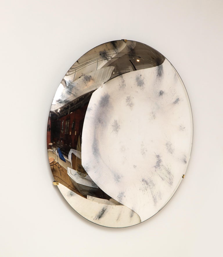 Large round frameless tinted glass in an antiqued silver color, thermoformed into a sculptural convex form and mirrored on back. Mounted on a brass three arm structure that is attached to wall. Only brass tips show on front. Hand casted in Milan,