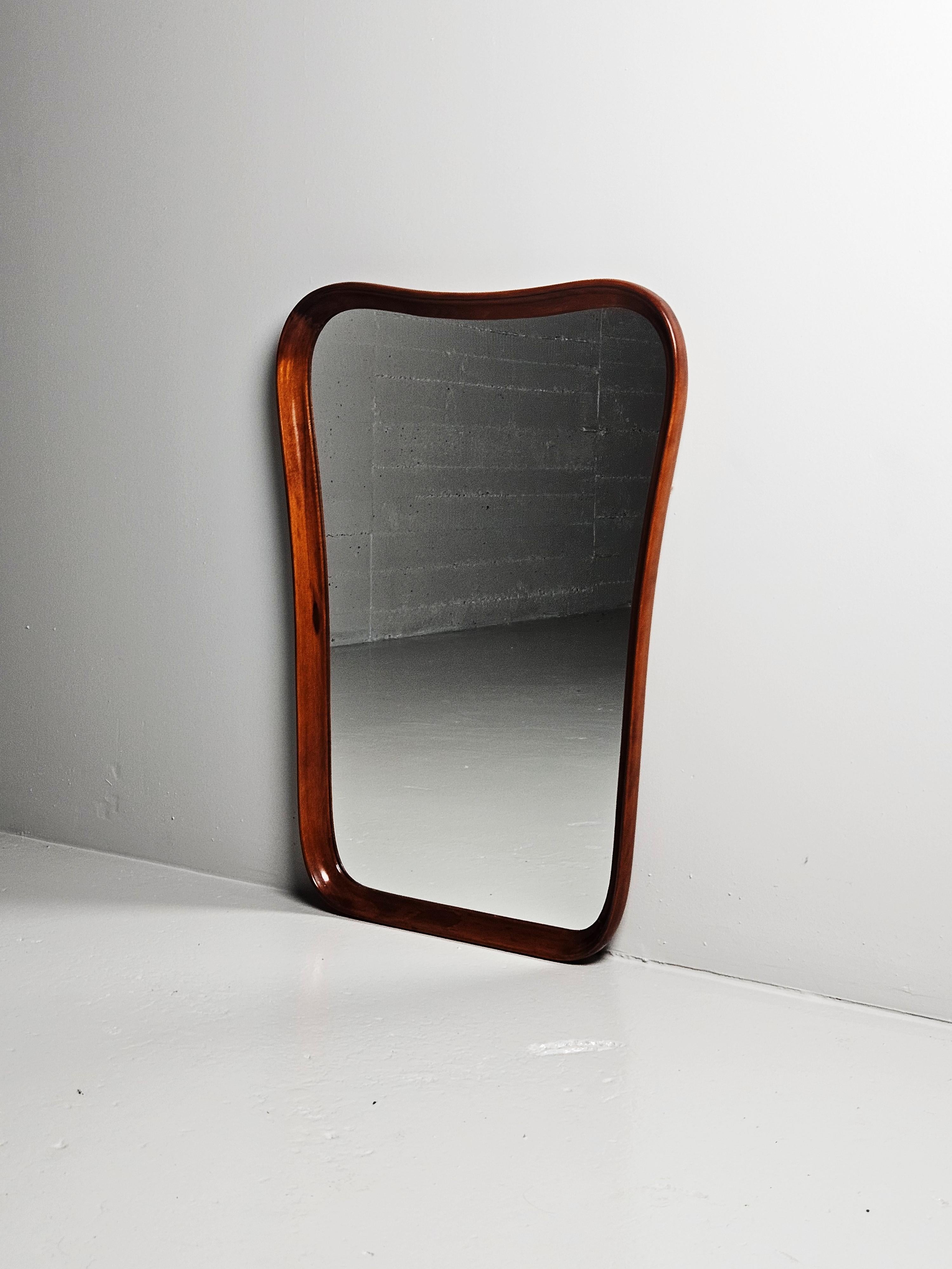 Large sculptural wall mirror produced in Sweden during the 1940s. 

The mirror frame is stained walnut wood and made with curvy sculptural lines.