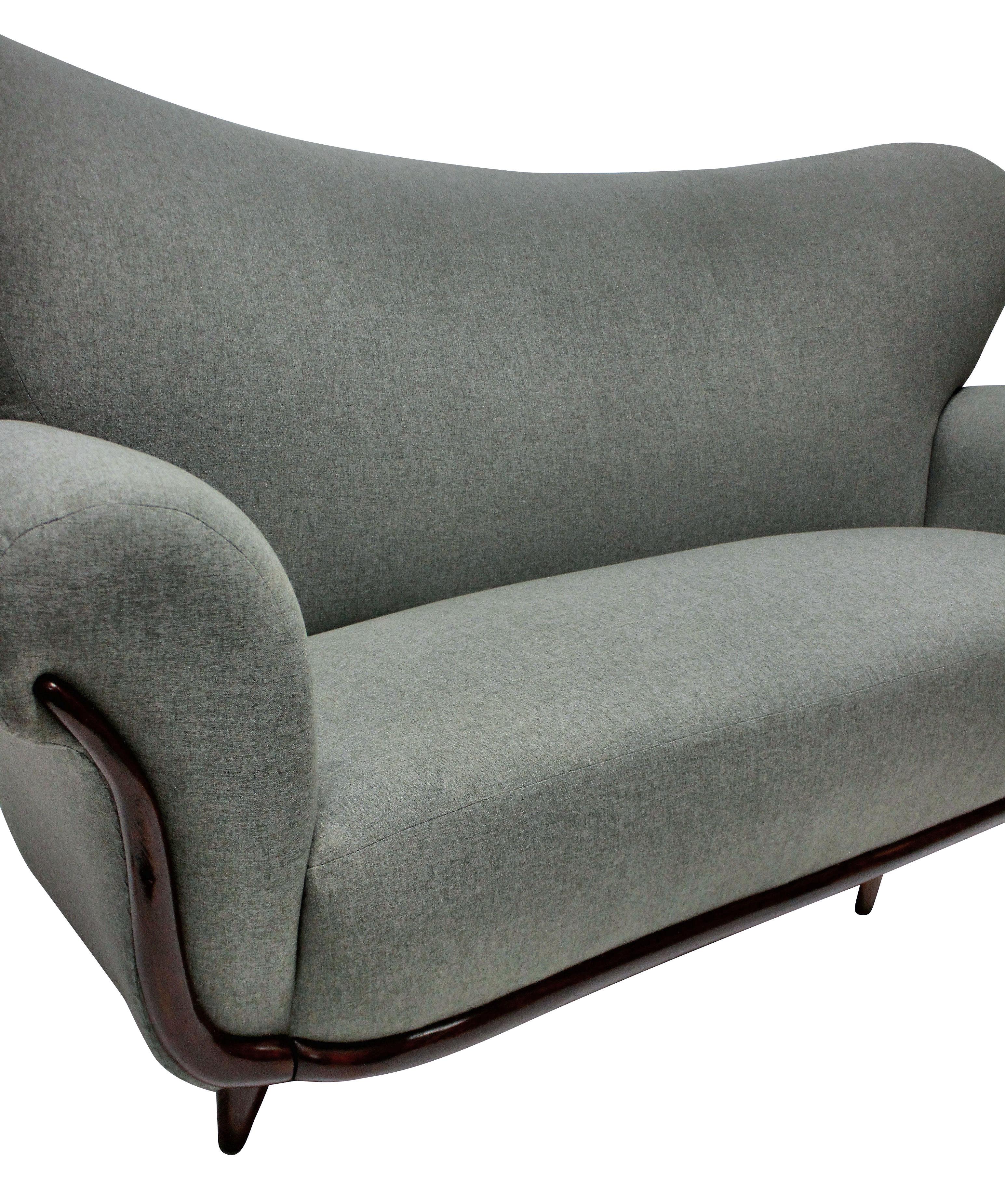 A large Italian sculptural sofa by Ulrich which is very comfortable. Newly upholstered in grey fabric and in a Minimalist fashion without piping or buttons, which accentuates the curved shapes. On tapering French polished feet and curved trim