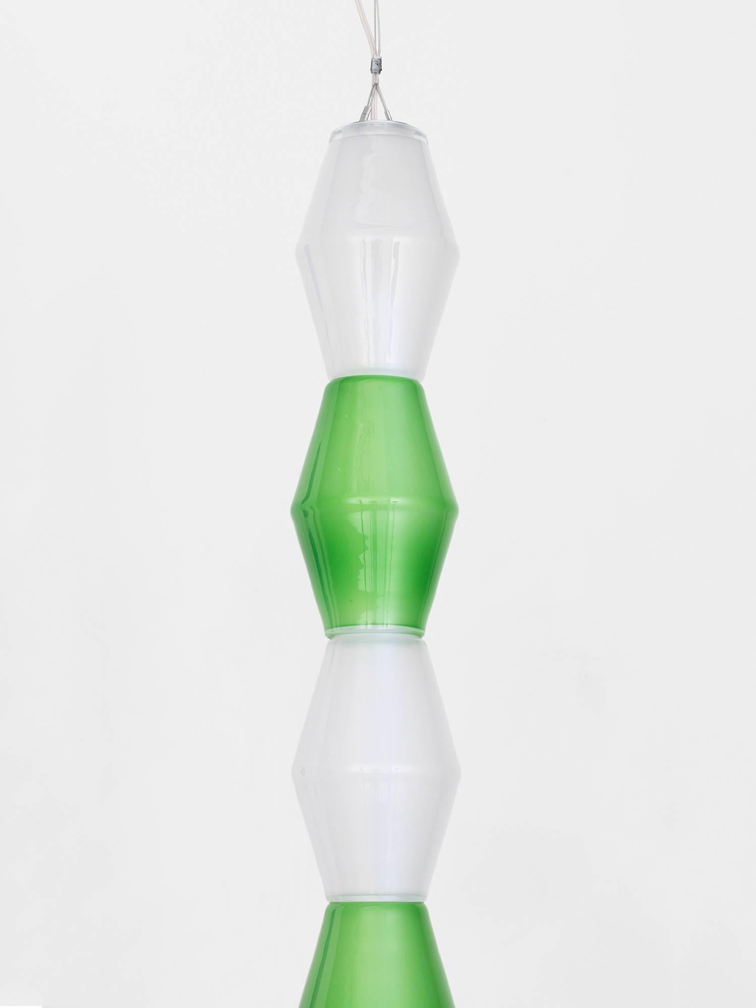 Suspension en verre totémique fabriquée à la main par l'artiste/architecte norvégien Tron Meyer. La lampe est composée de onze formes en verre vert et blanc enroulées autour d'un noyau de LED, qui ont été soufflées à la main dans un moule en bois