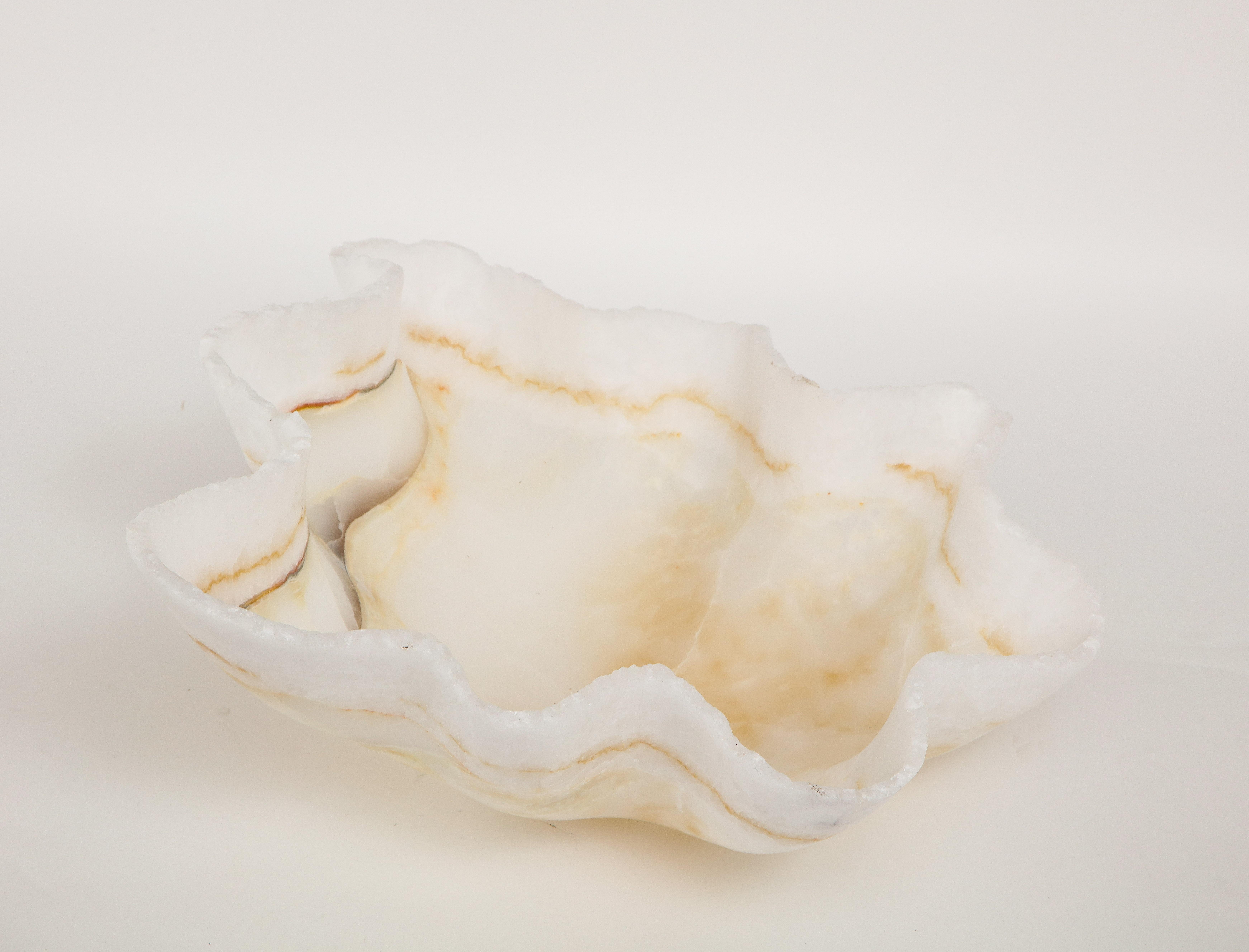 A large sculptural white hand carved raw edge onyx bowl or centerpiece in an impressive size banded with pale undulating bands of amber and gold. Utilitarian and stunning, this centerpiece works with a variety of styles including, Mid-Century