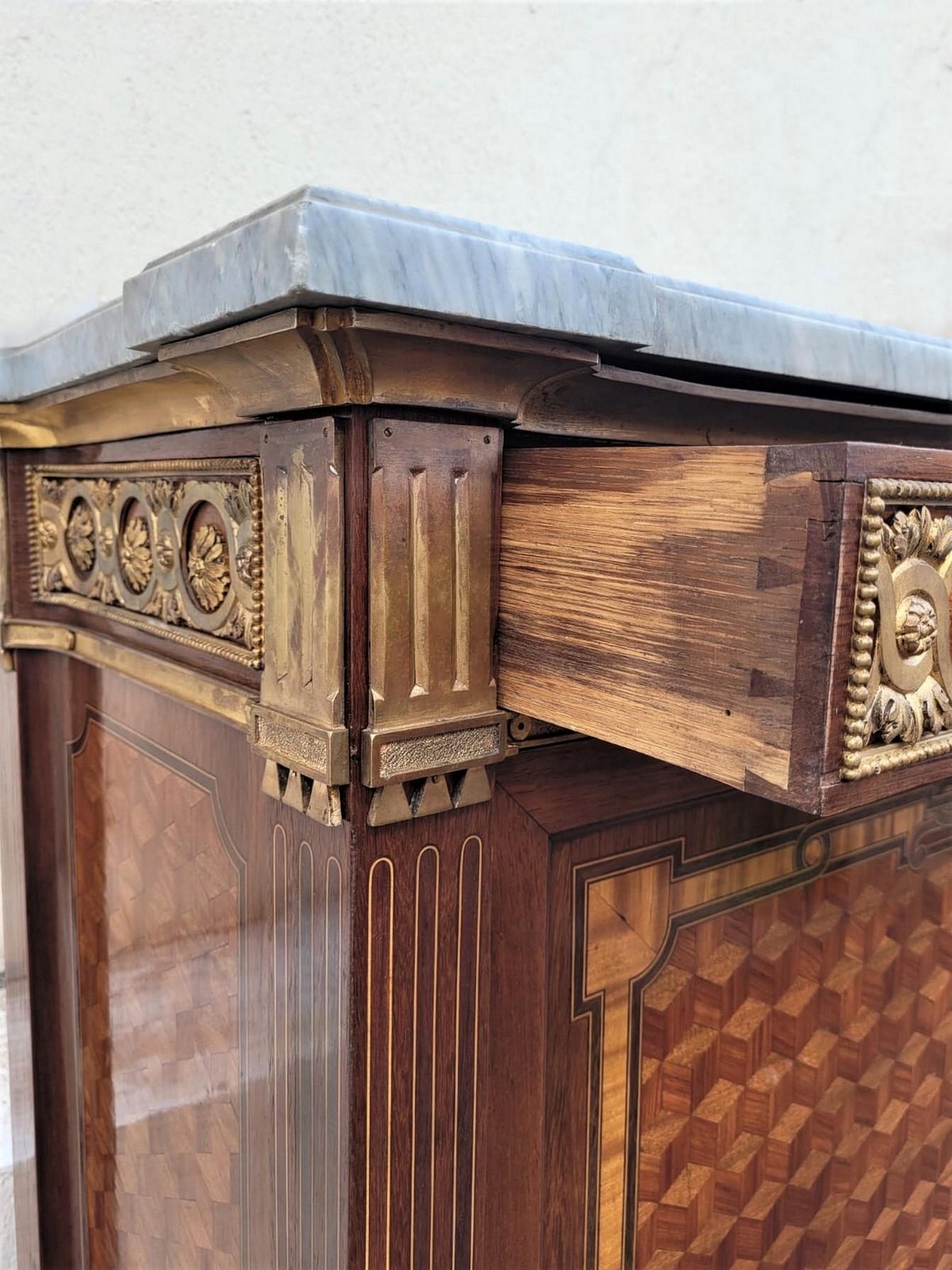 Massive secretaire with flap in marquetry of cubes on the doors and sides and bronzes (partly gilded): the flap covered with leather inside opens on a series of 4 drawers in solid mahogany and shelves.

It is surmounted by a gray marble top

Good